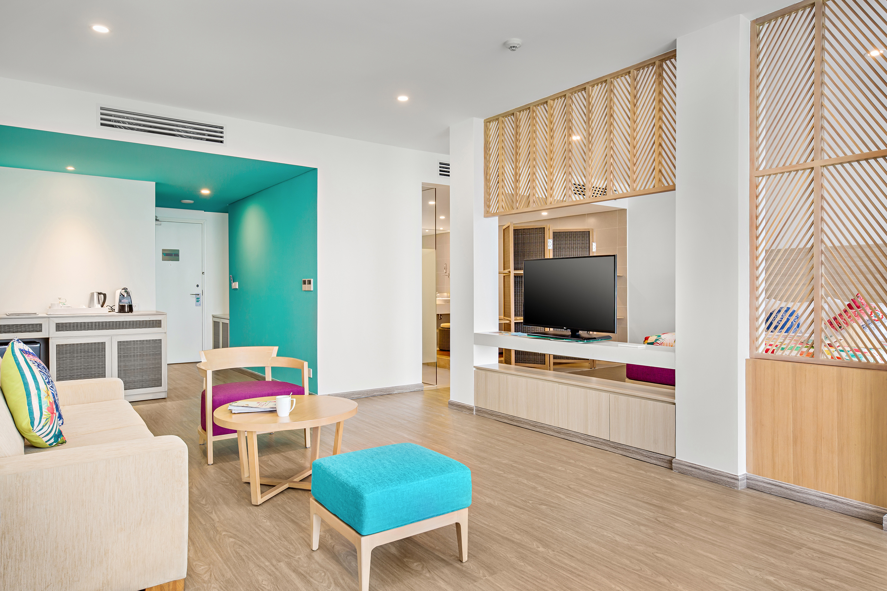 Contemporary hotel suite living area with turquoise and wood accents.