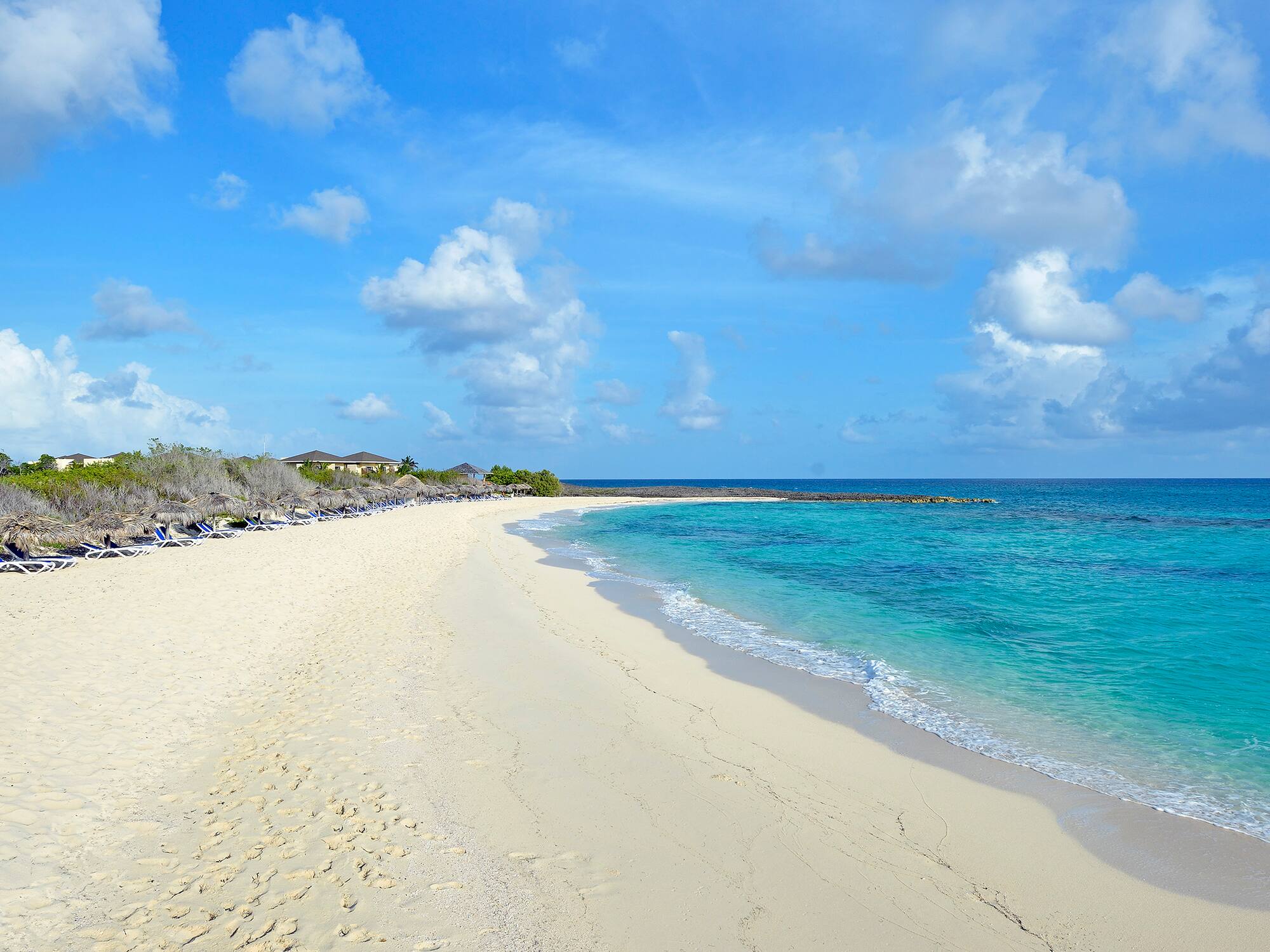 a beach with blue water and clouds