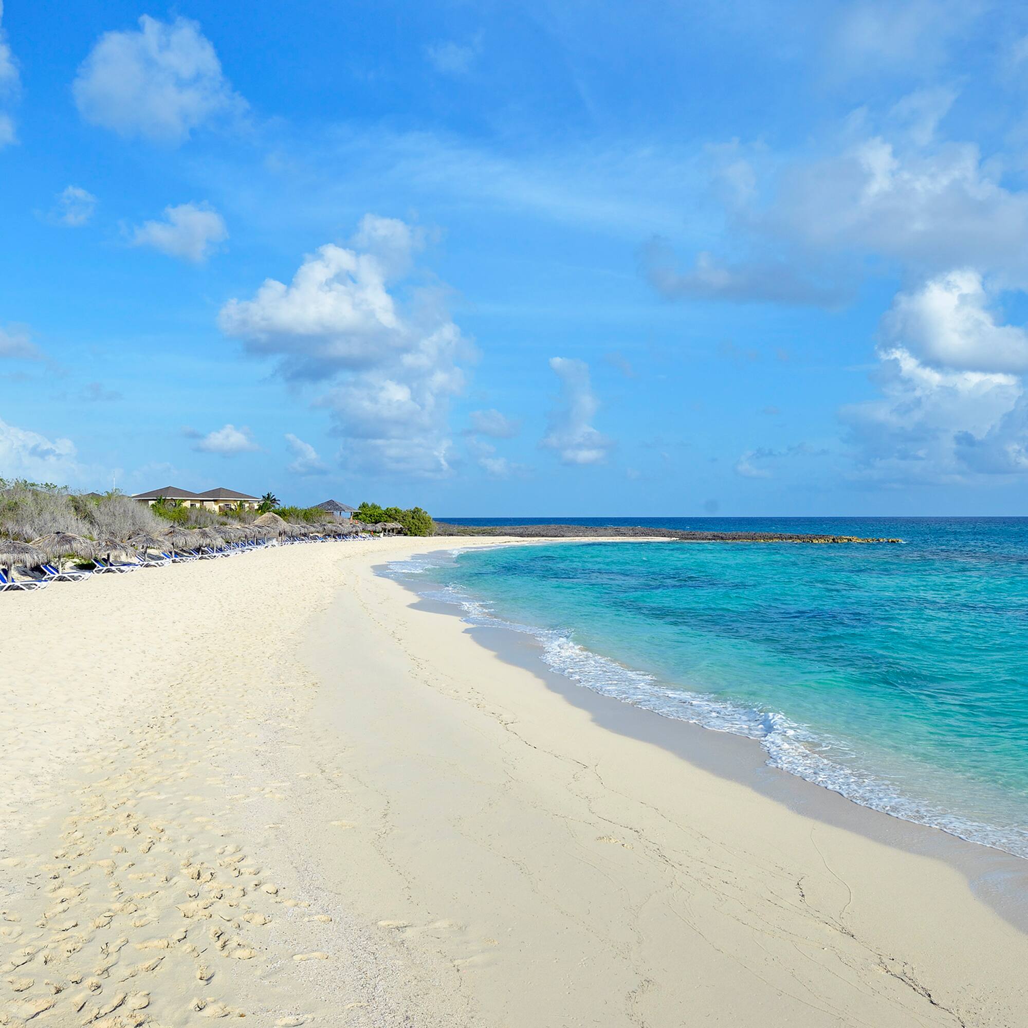 a beach with blue water and clouds