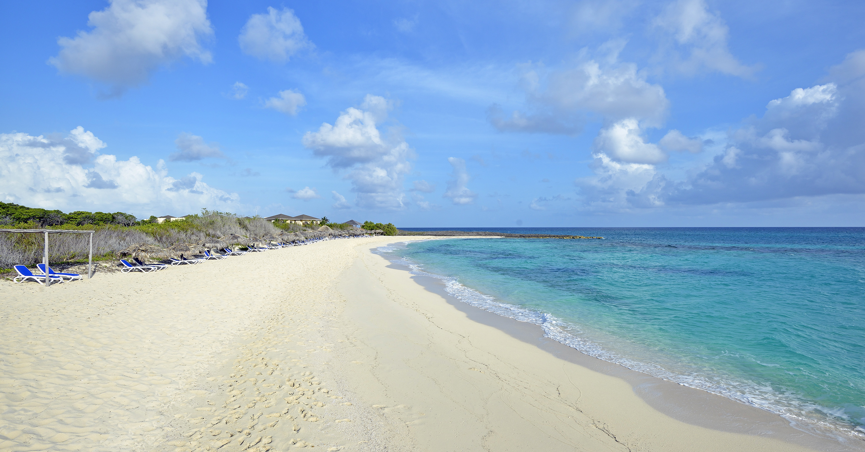 a beach with blue water and clouds