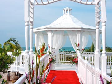 a white gazebo with red carpet and flowers