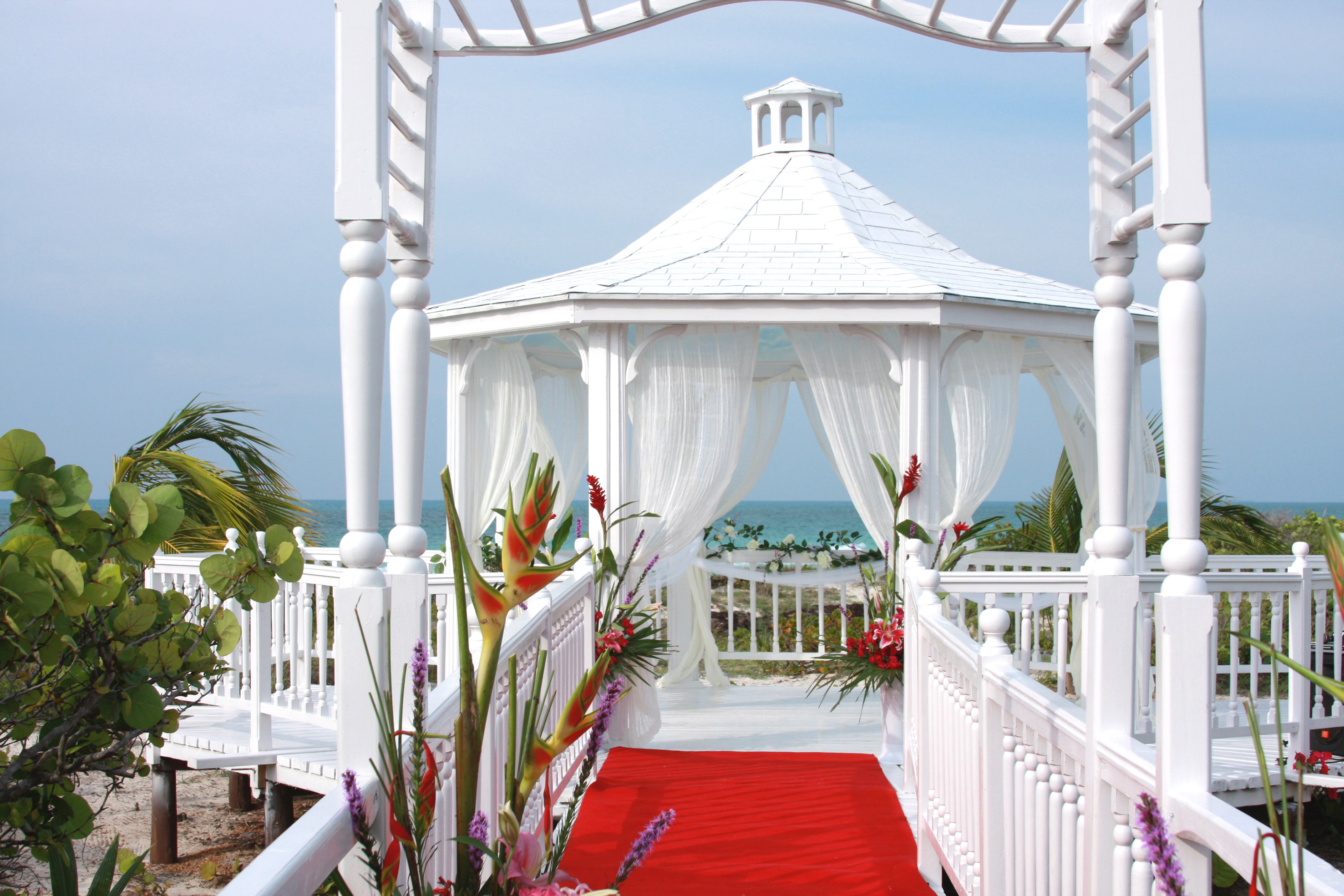 a white gazebo with red carpet and flowers