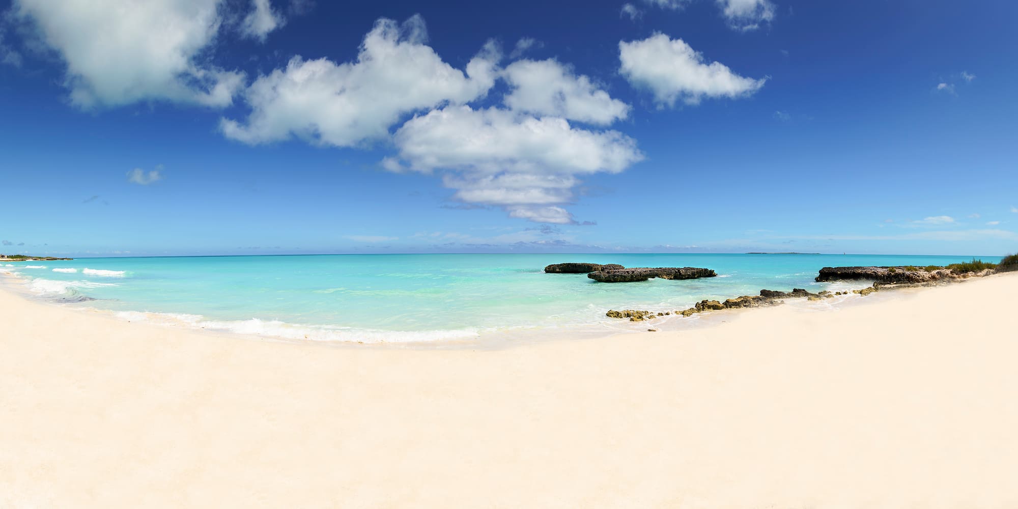 a beach with rocks and blue water