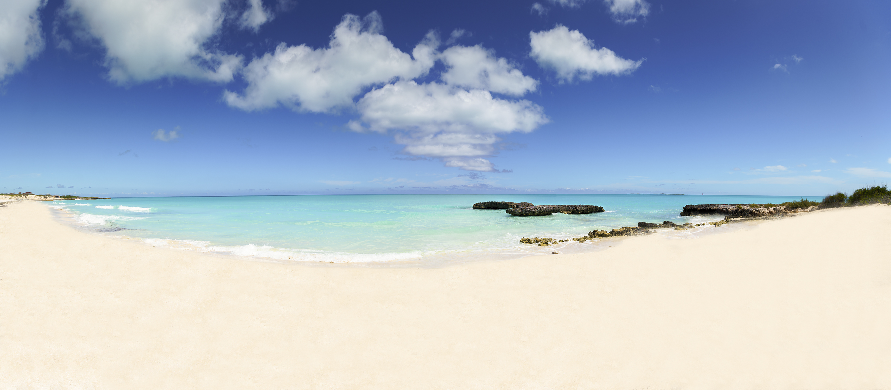 a beach with rocks and blue water