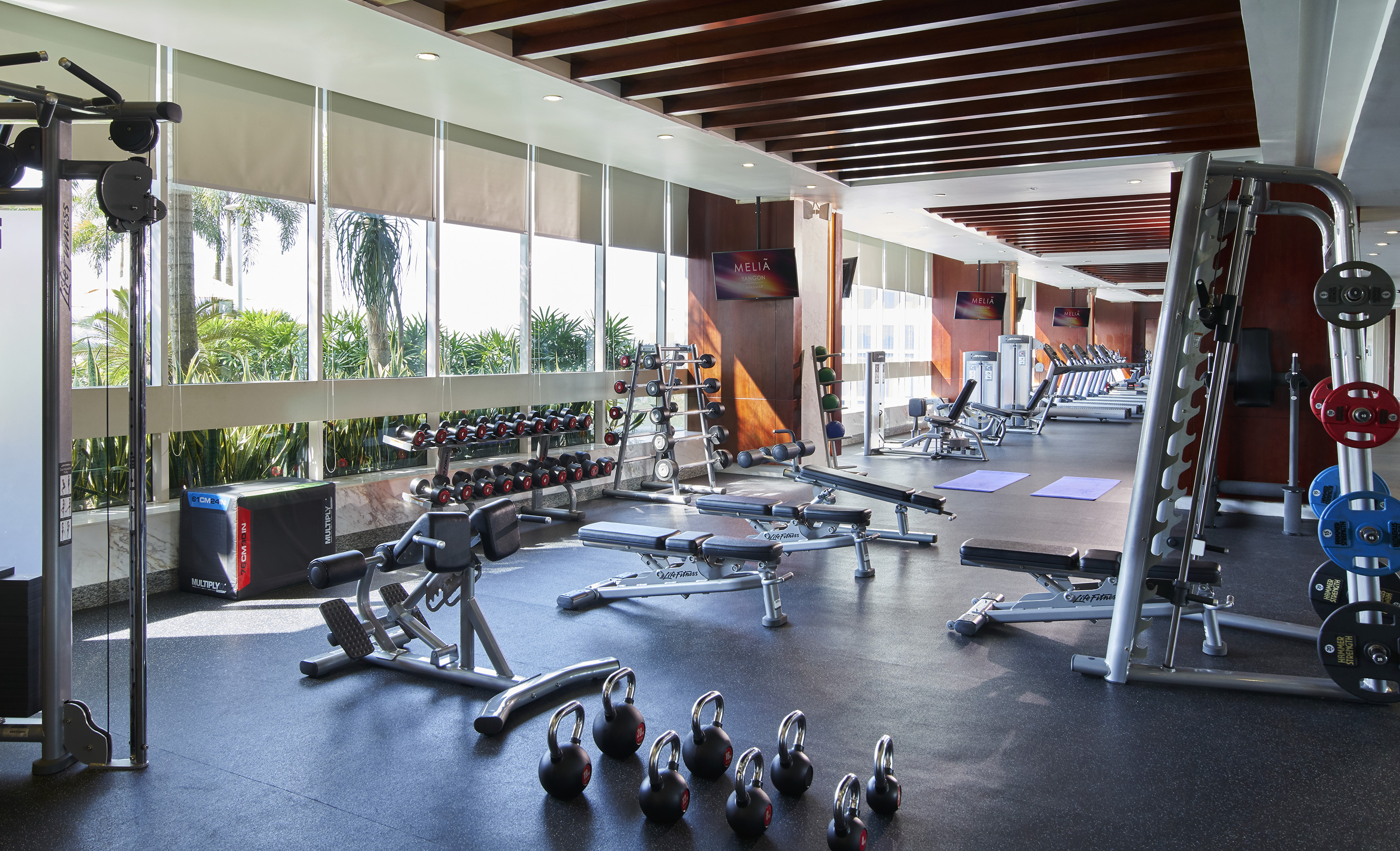 Meliá hotel gym with diverse fitness equipment, dumbbells, treadmills, and bright windows.