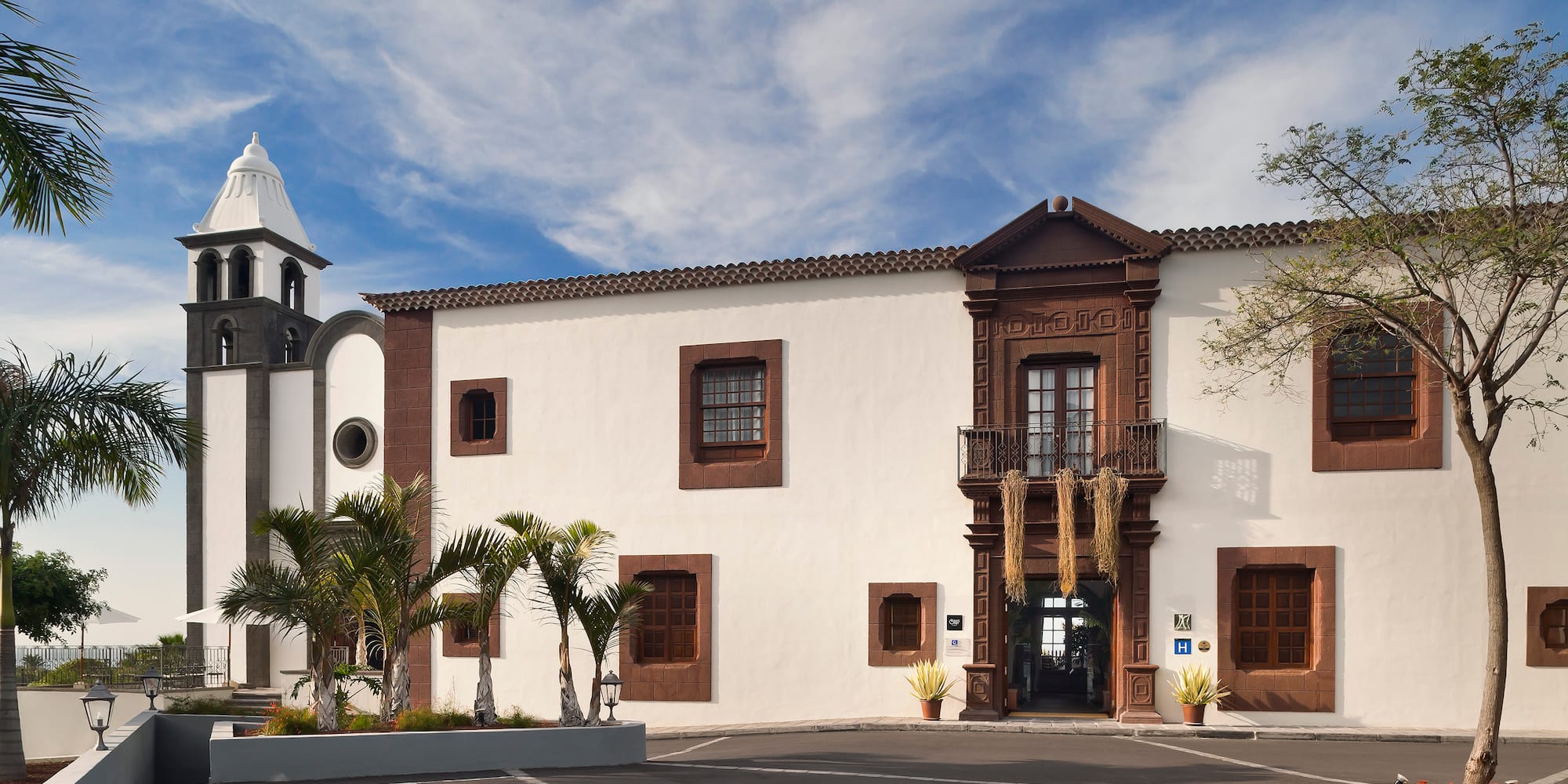 a white building with a bell tower and palm trees