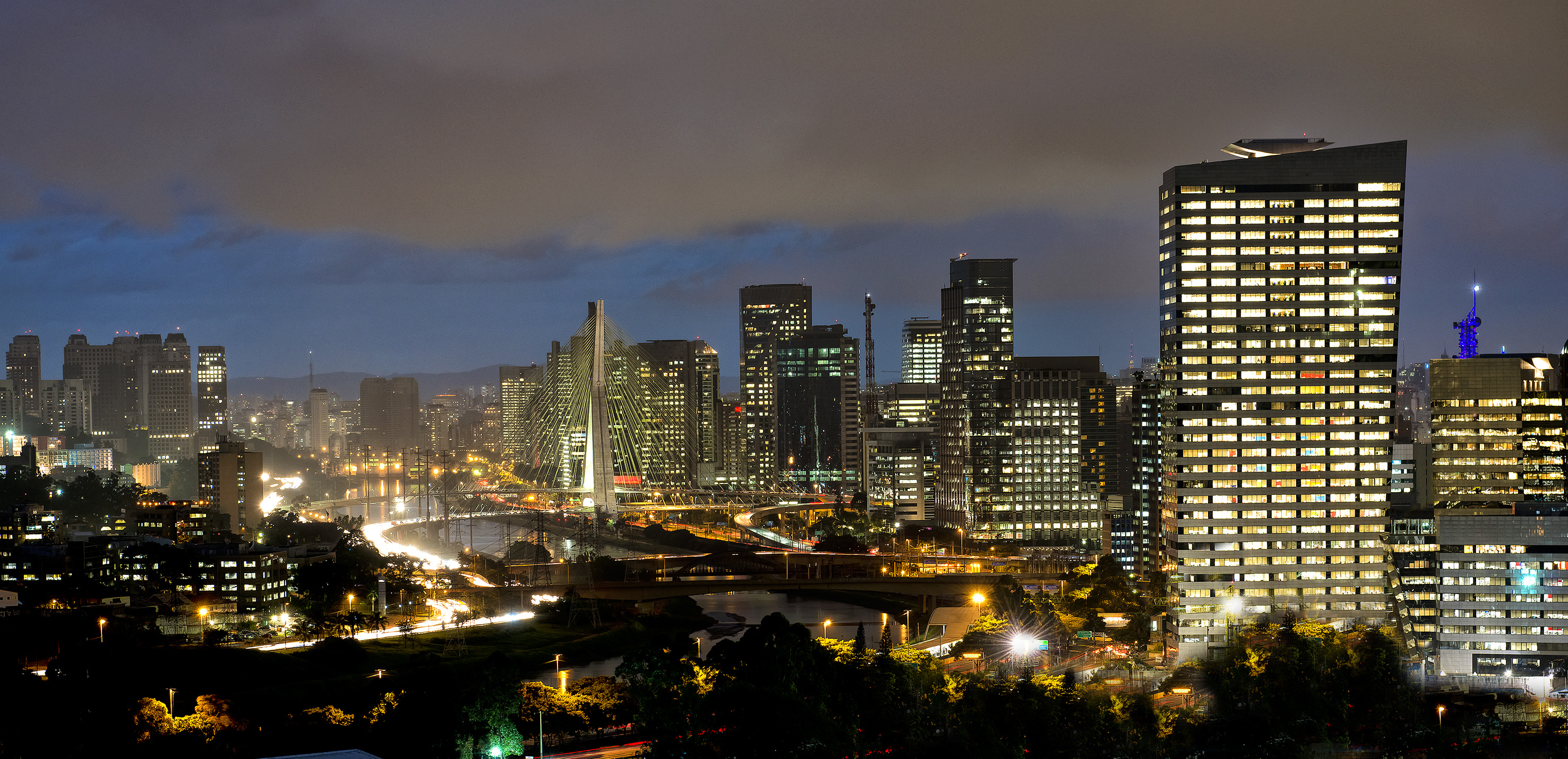 São Paulo cityscape at night, illuminated buildings, and cable-stayed bridge.