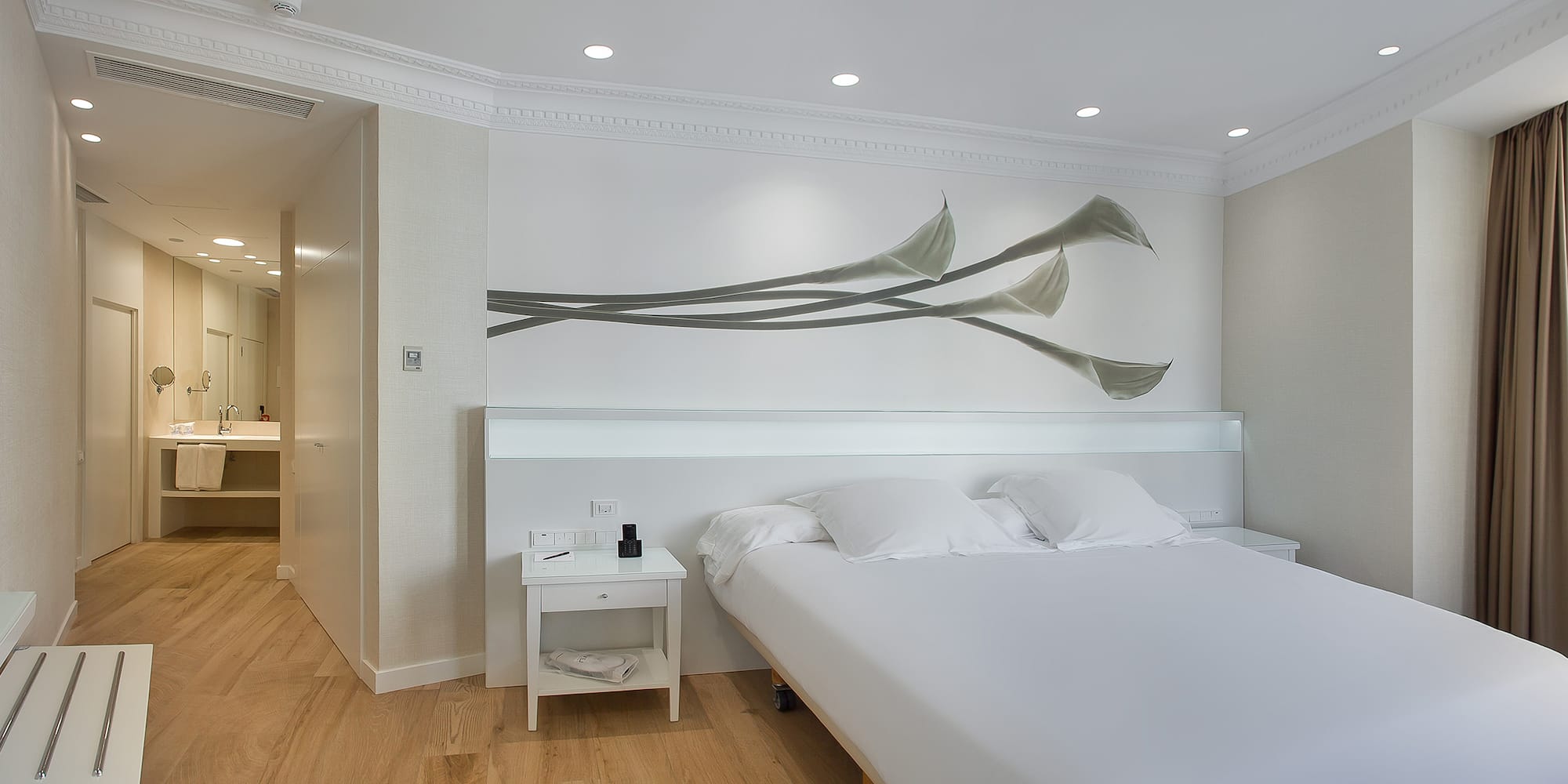 a bed with white sheets and pillows in a room with a white wall