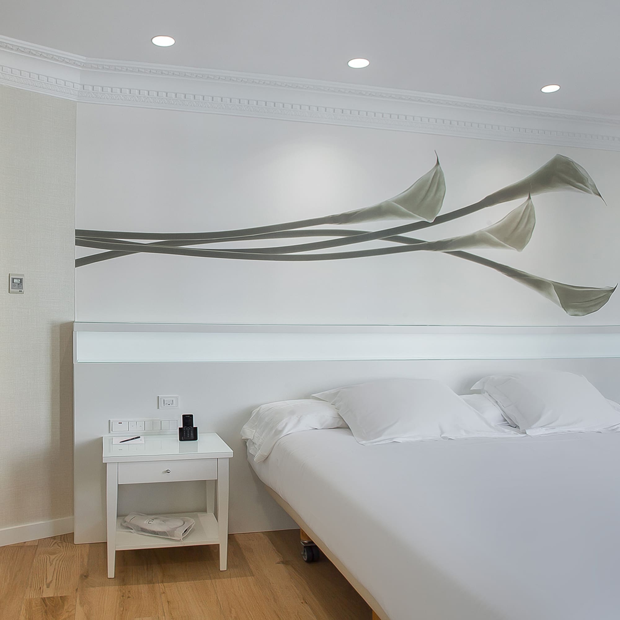 a bed with white sheets and pillows in a room with a white wall