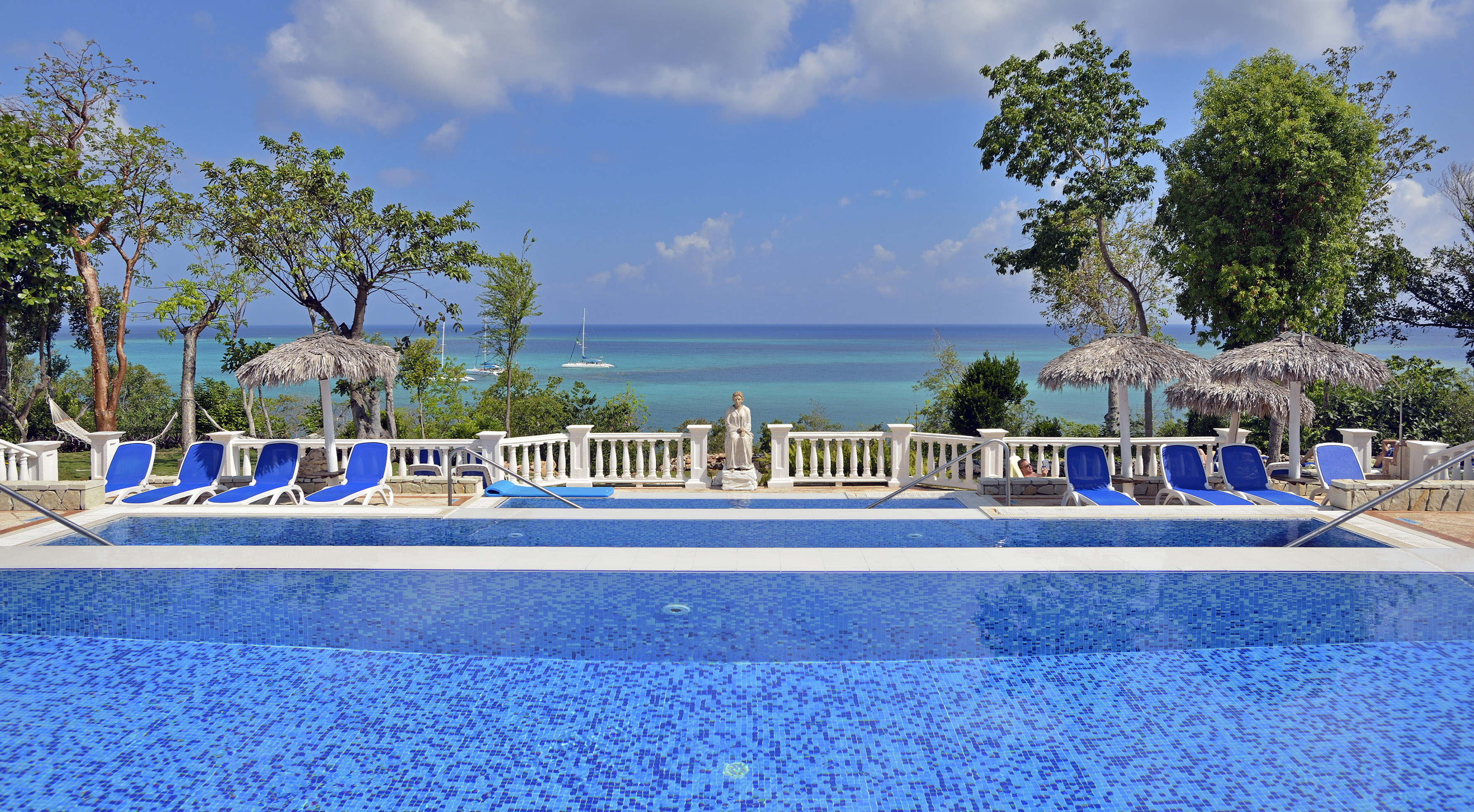 a pool with a statue and a body of water in the background