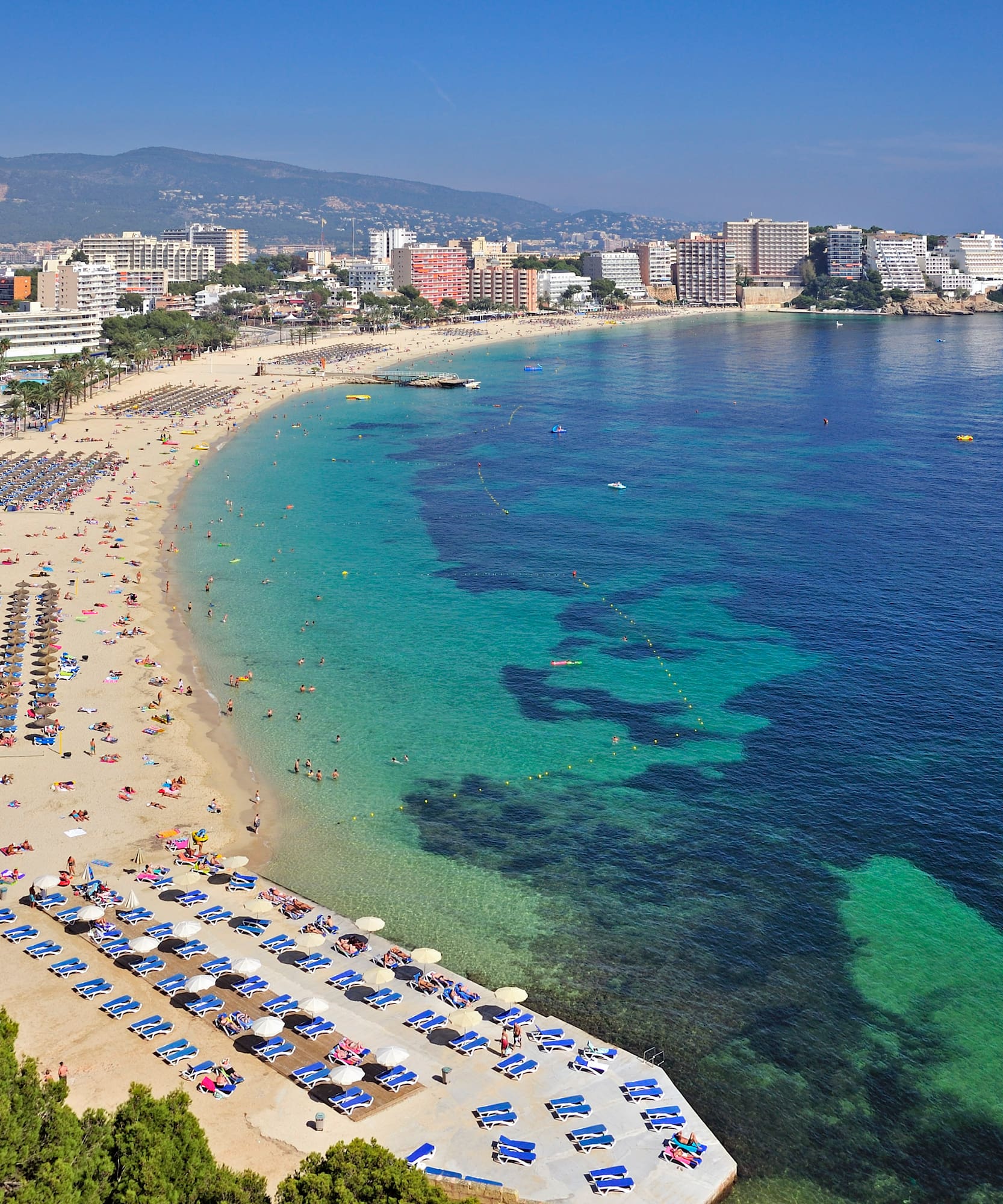 a beach with umbrellas and chairs and buildings in the background