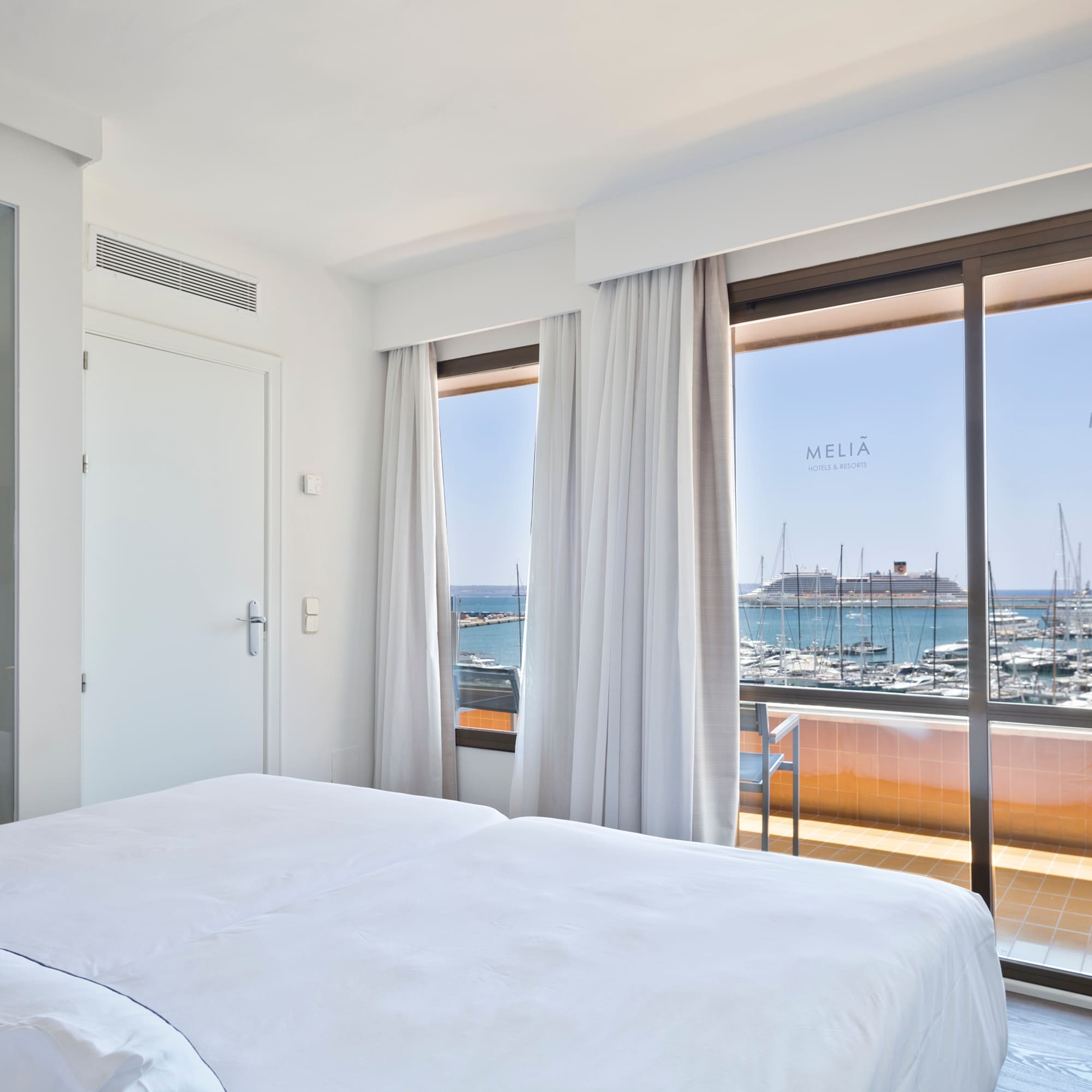 a room with a bed and a view of the water and boats