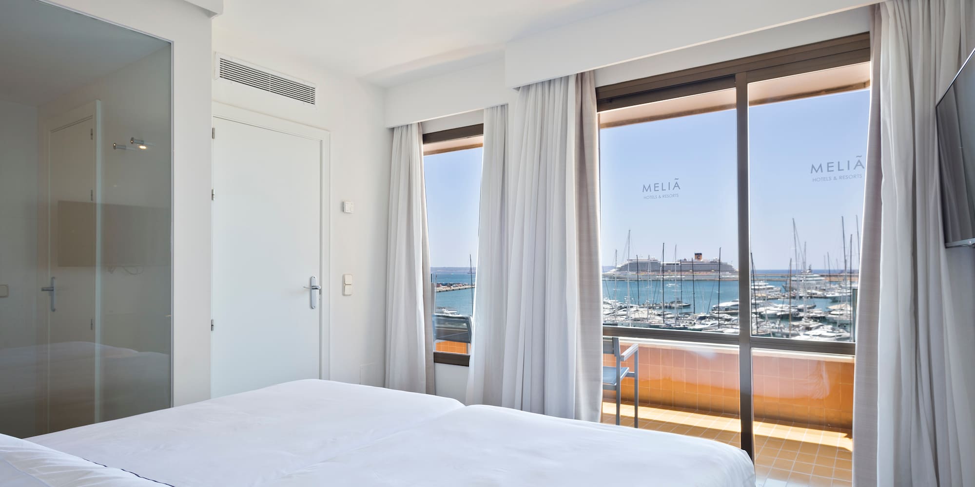 a room with a bed and a view of the water and boats