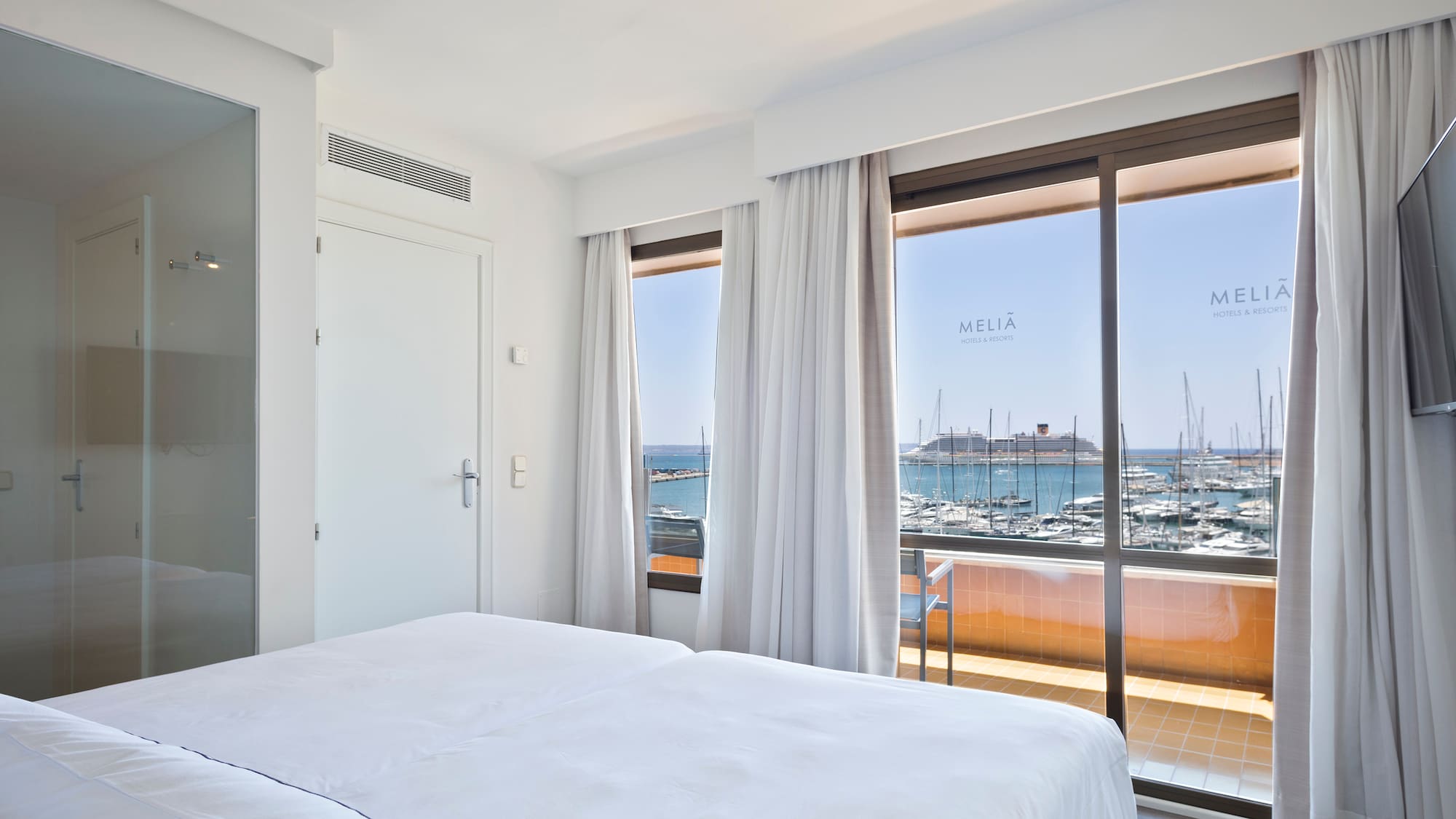 a room with a bed and a view of the water and boats