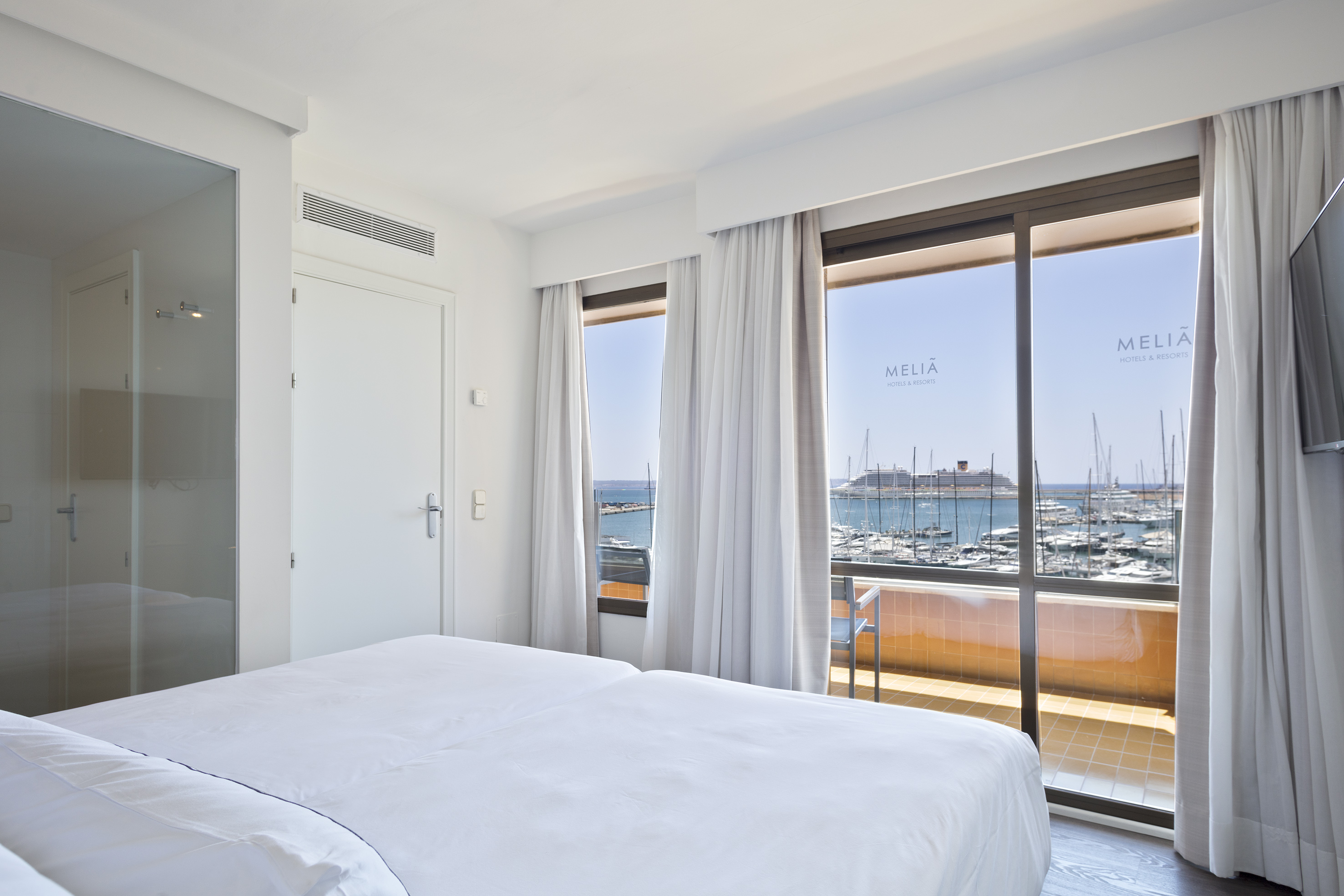 a room with a bed and a view of the water and boats