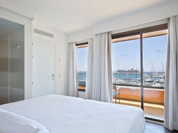 a room with a bed and a view of the water and boats
