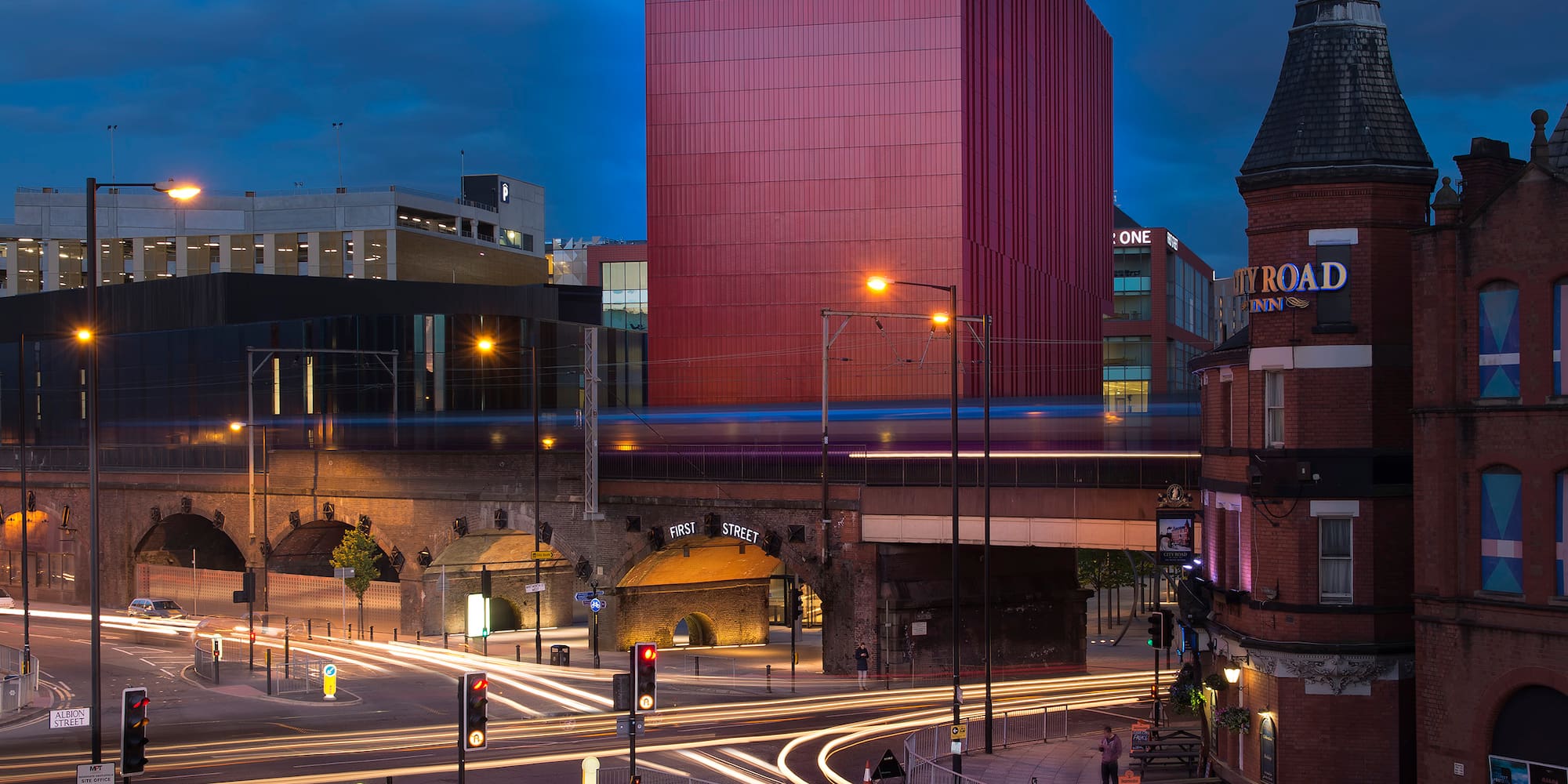 a city street with a red building and a bridge