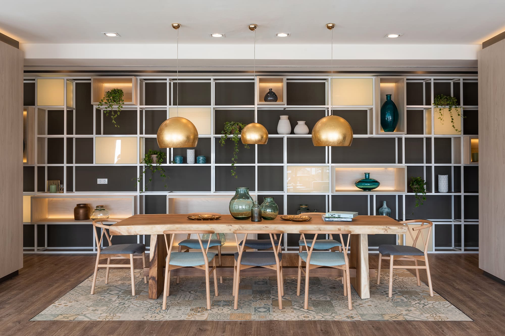 Modern dining room, wood table, gold pendant lights, and modular wall shelving.