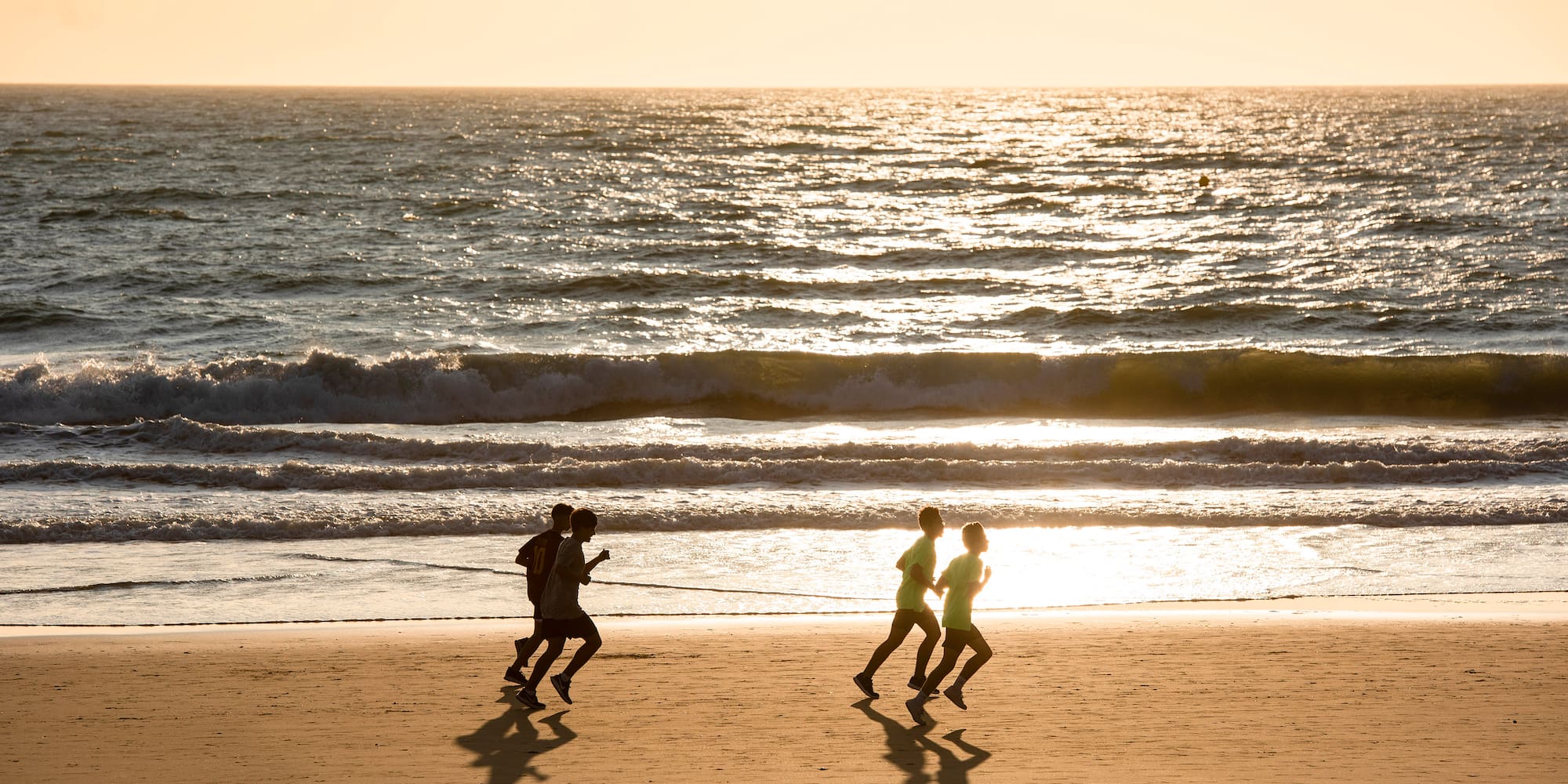 a group of people running on a beach