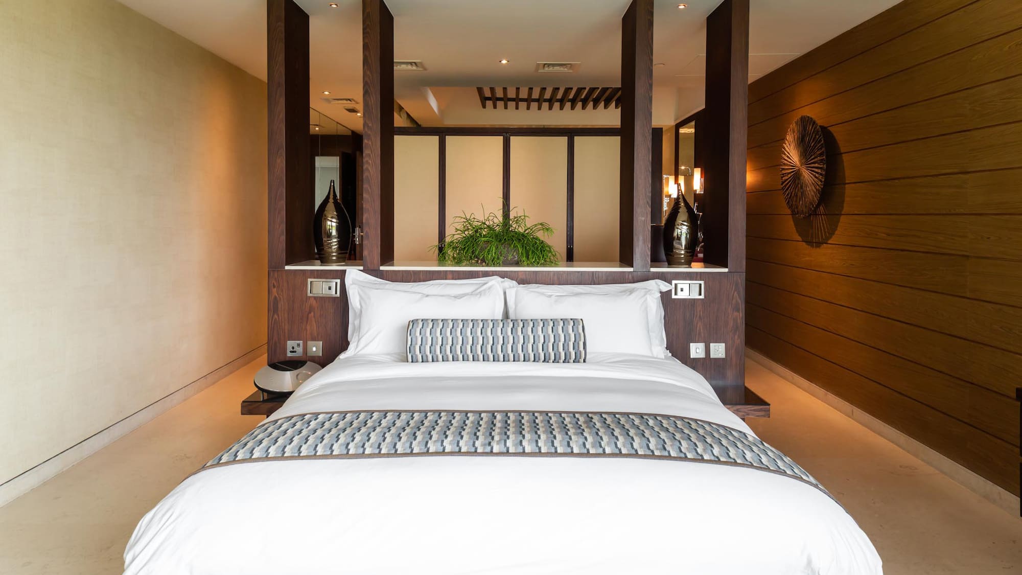 a bed with white pillows and a wood wall