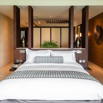 a bed with white pillows and a wood wall
