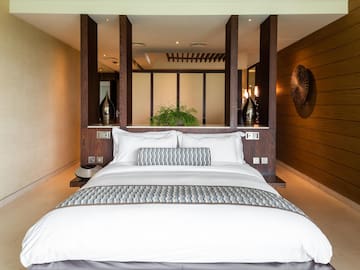 a bed with white pillows and a wood wall