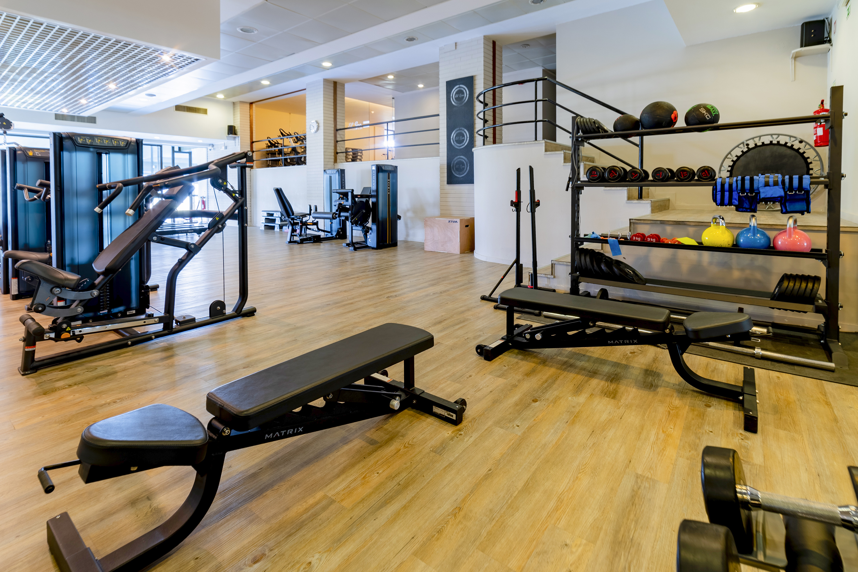 Modern gym with diverse exercise equipment, free weights, and workout benches.