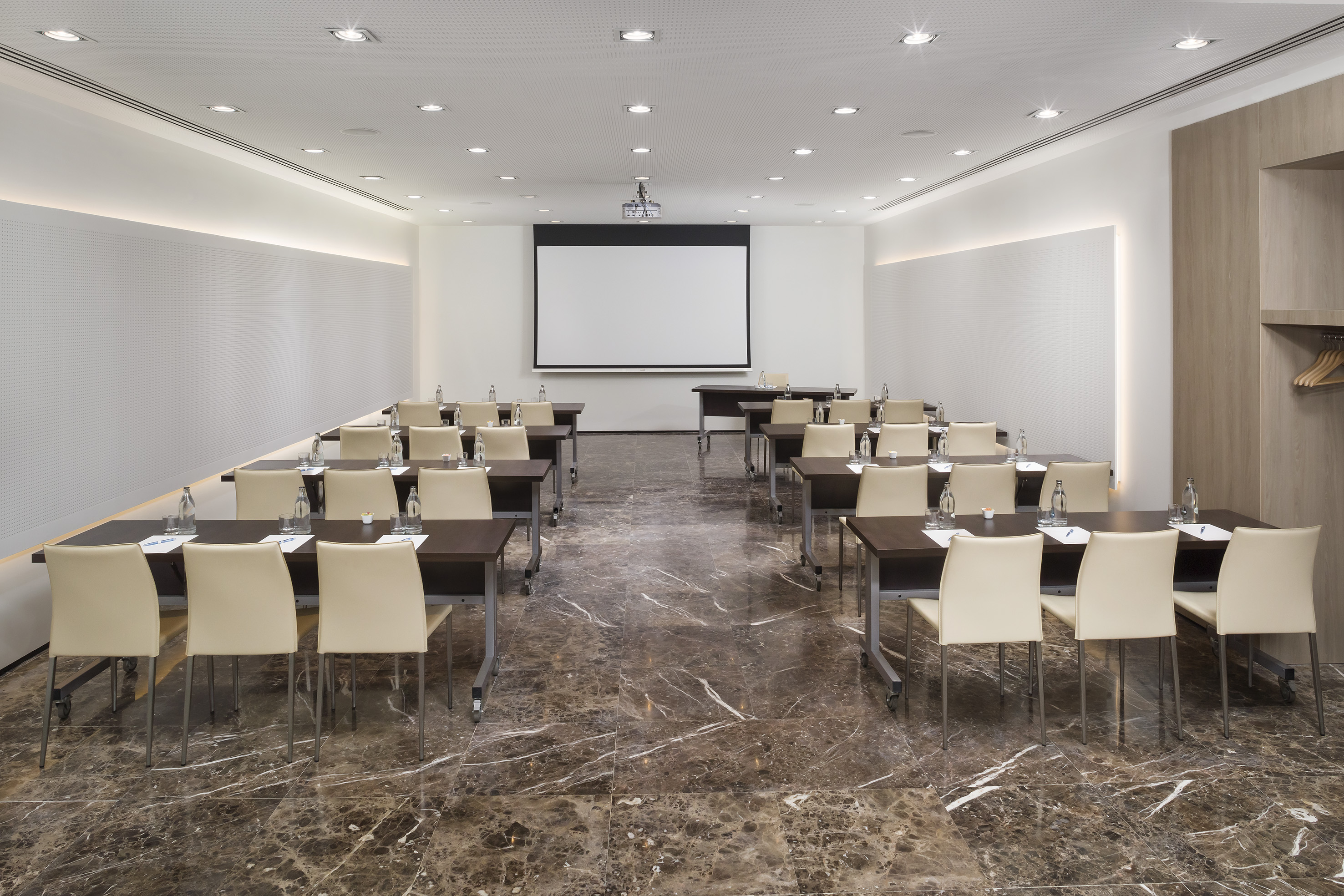 Modern conference room with tables, chairs, projector screen, and marble floor.
