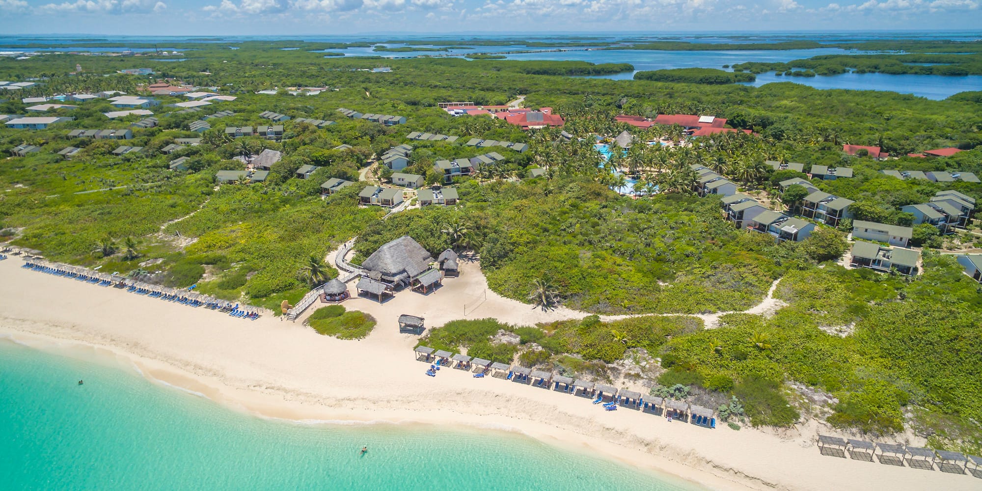 a beach with a group of houses and a body of water