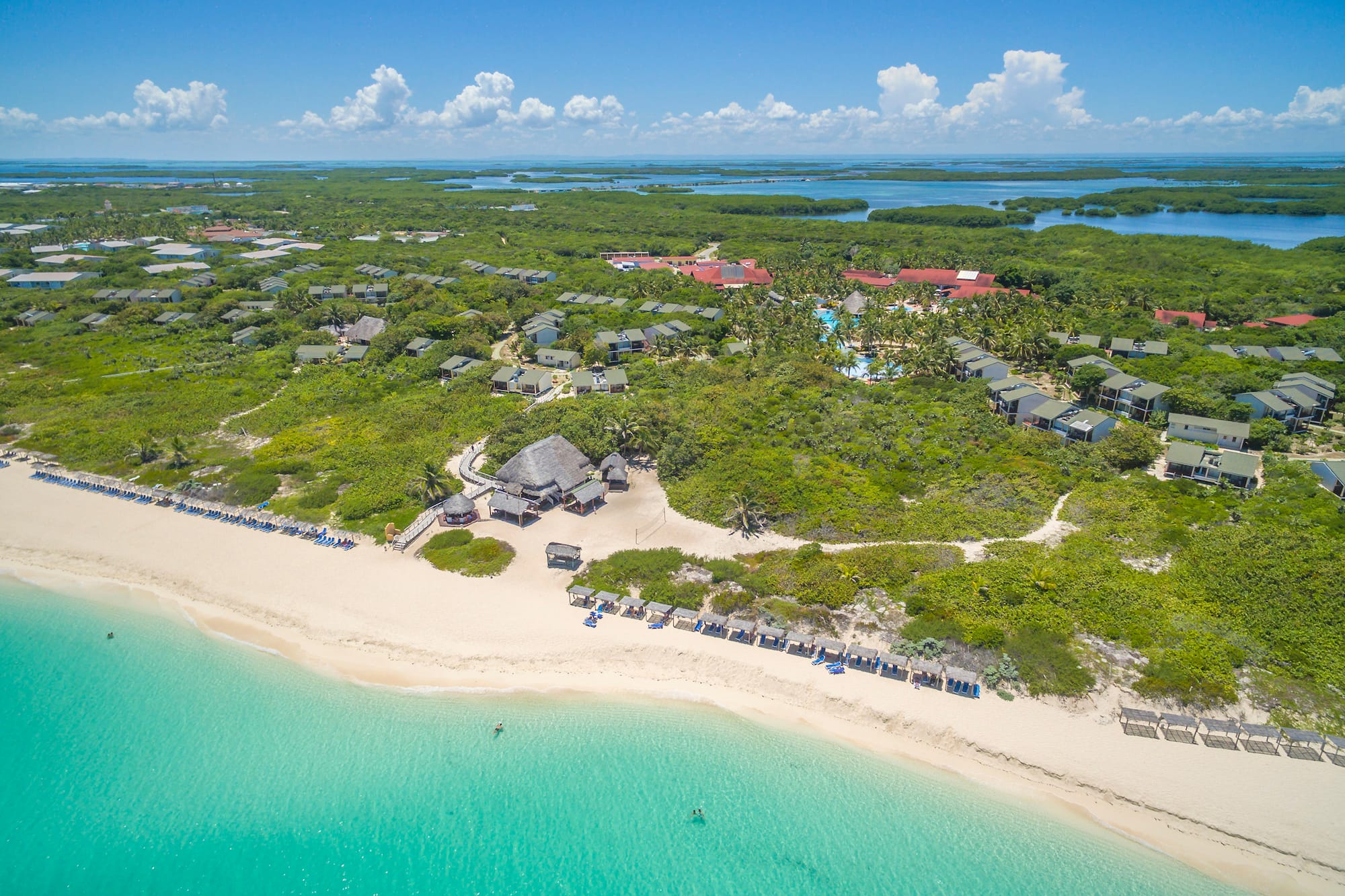 a beach with a group of houses and a body of water