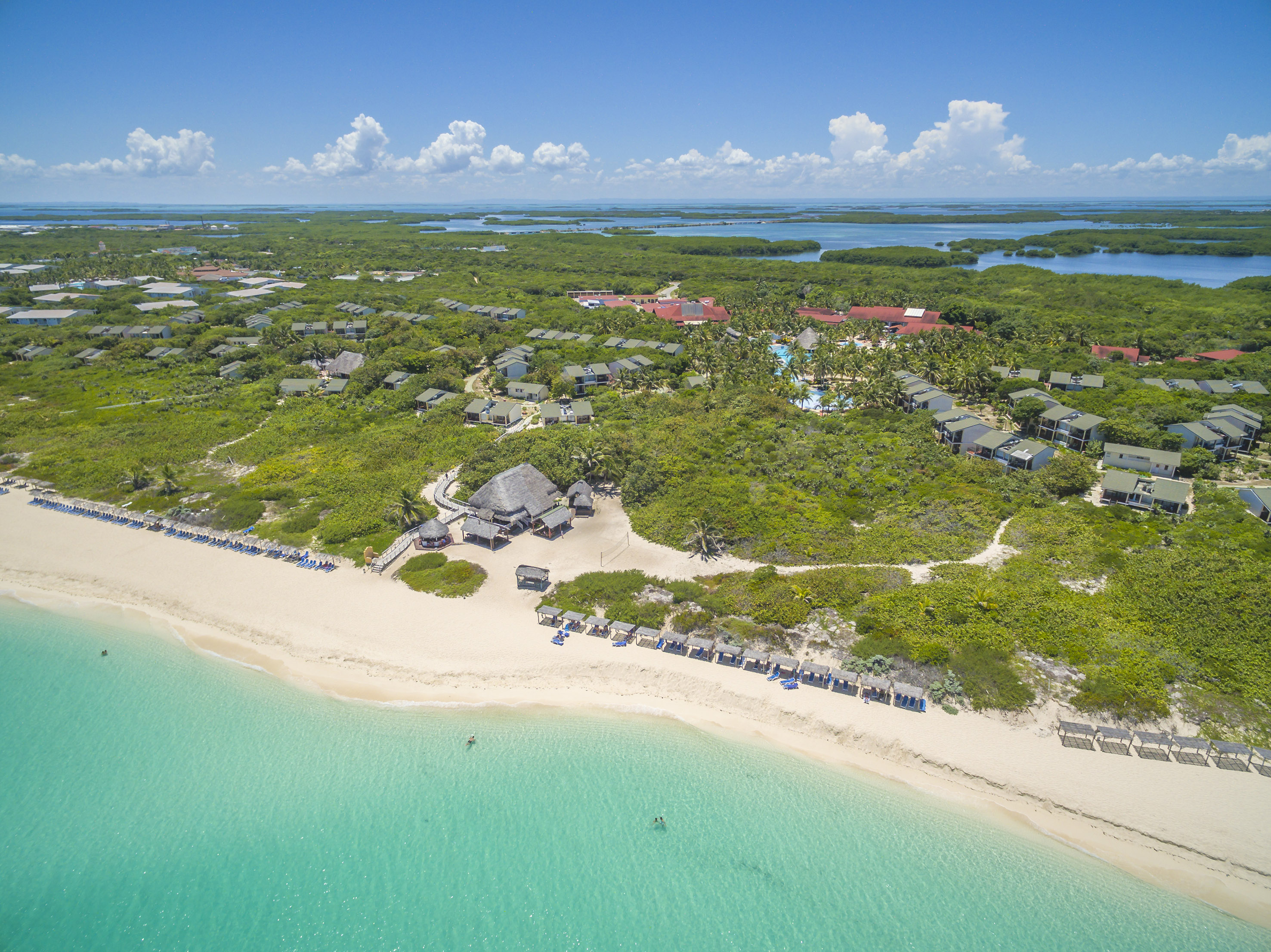 a beach with a group of houses and a body of water