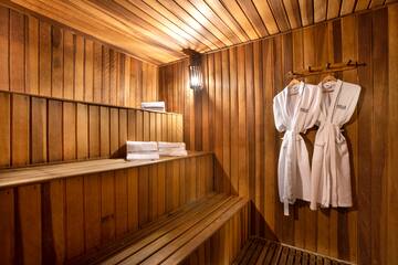 a wooden sauna with white bathrobes and towels