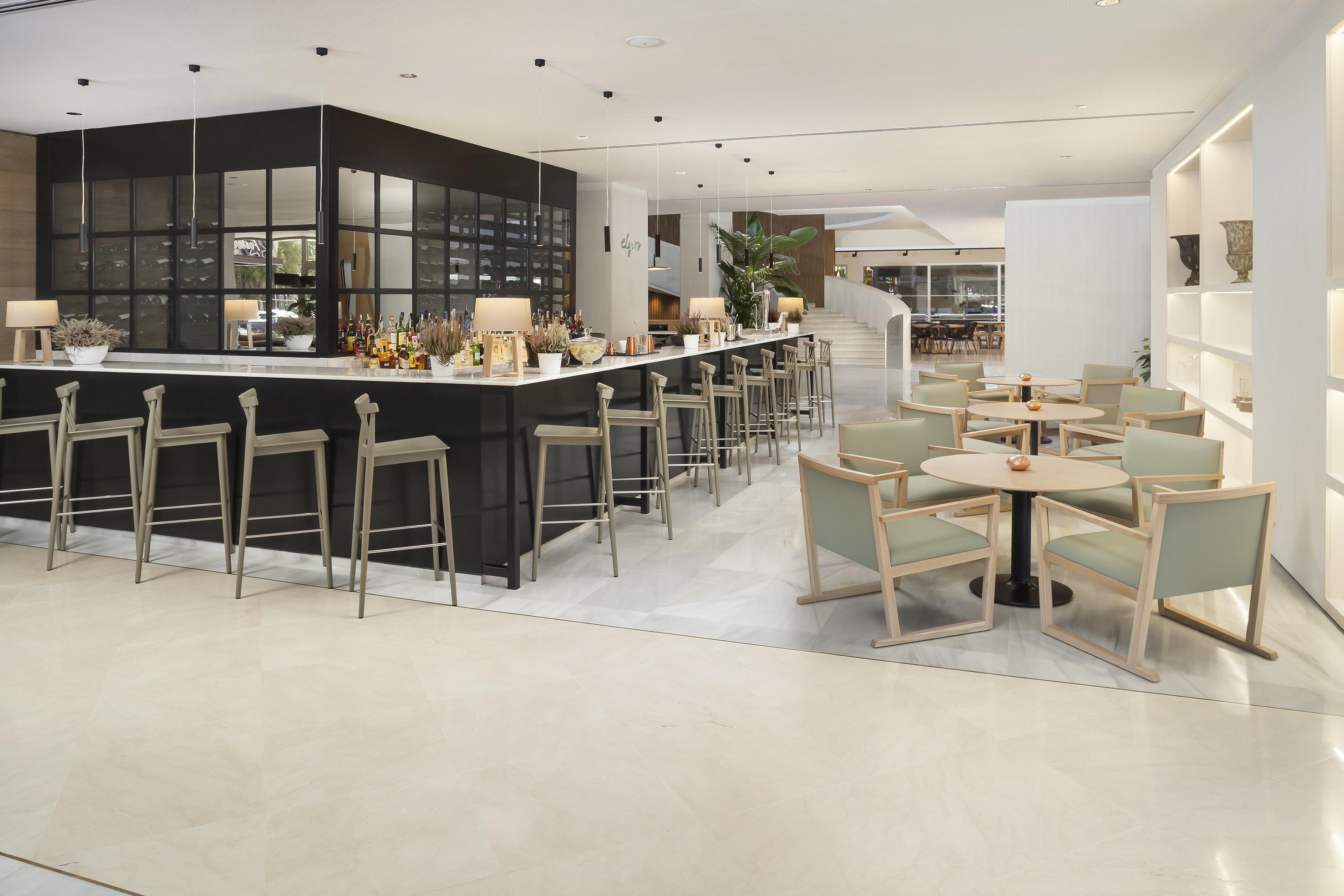 Stylish hotel lobby bar with black counter, stools, and green lounge seating.