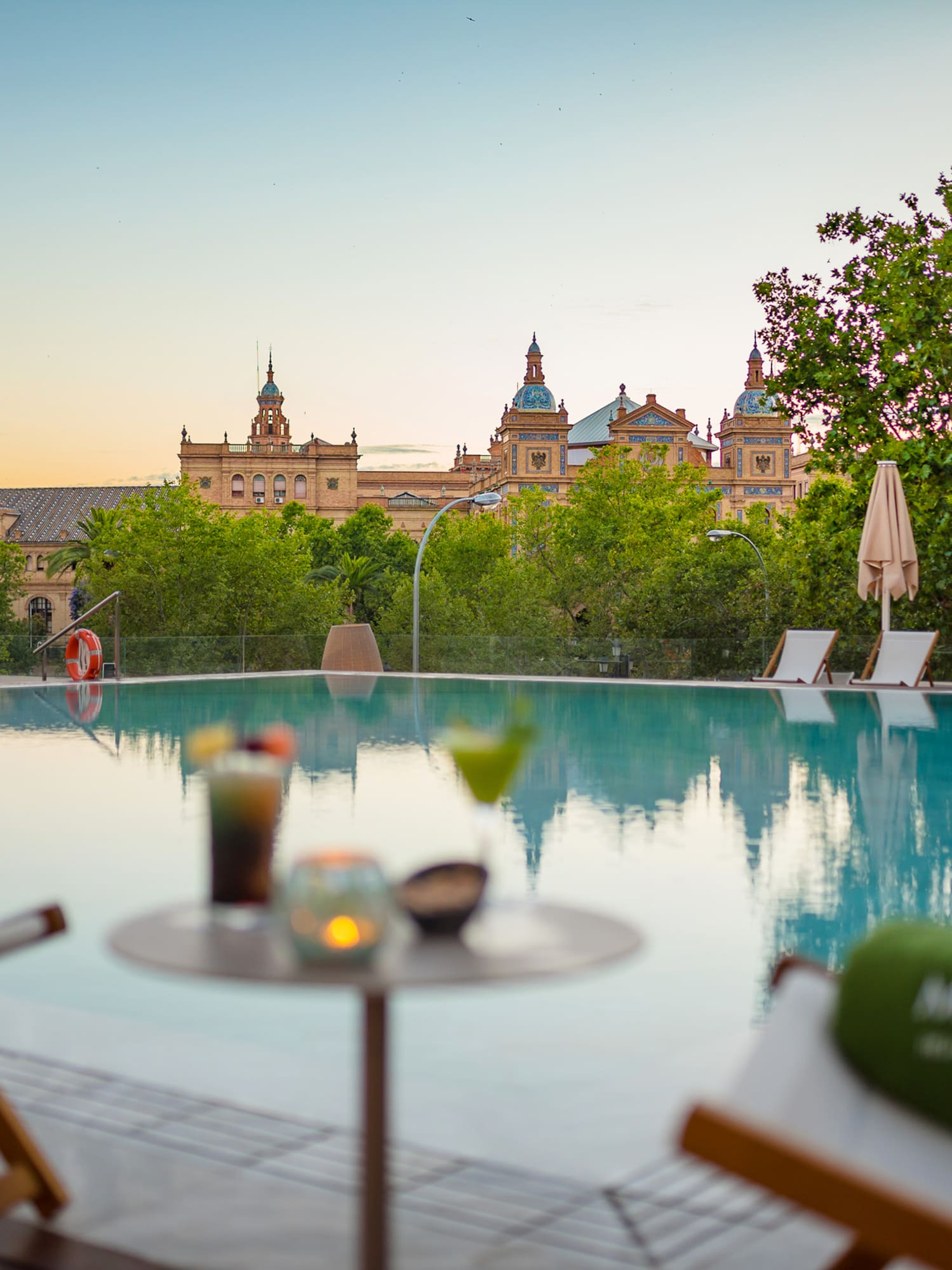 a pool with chairs and a table with a building in the background