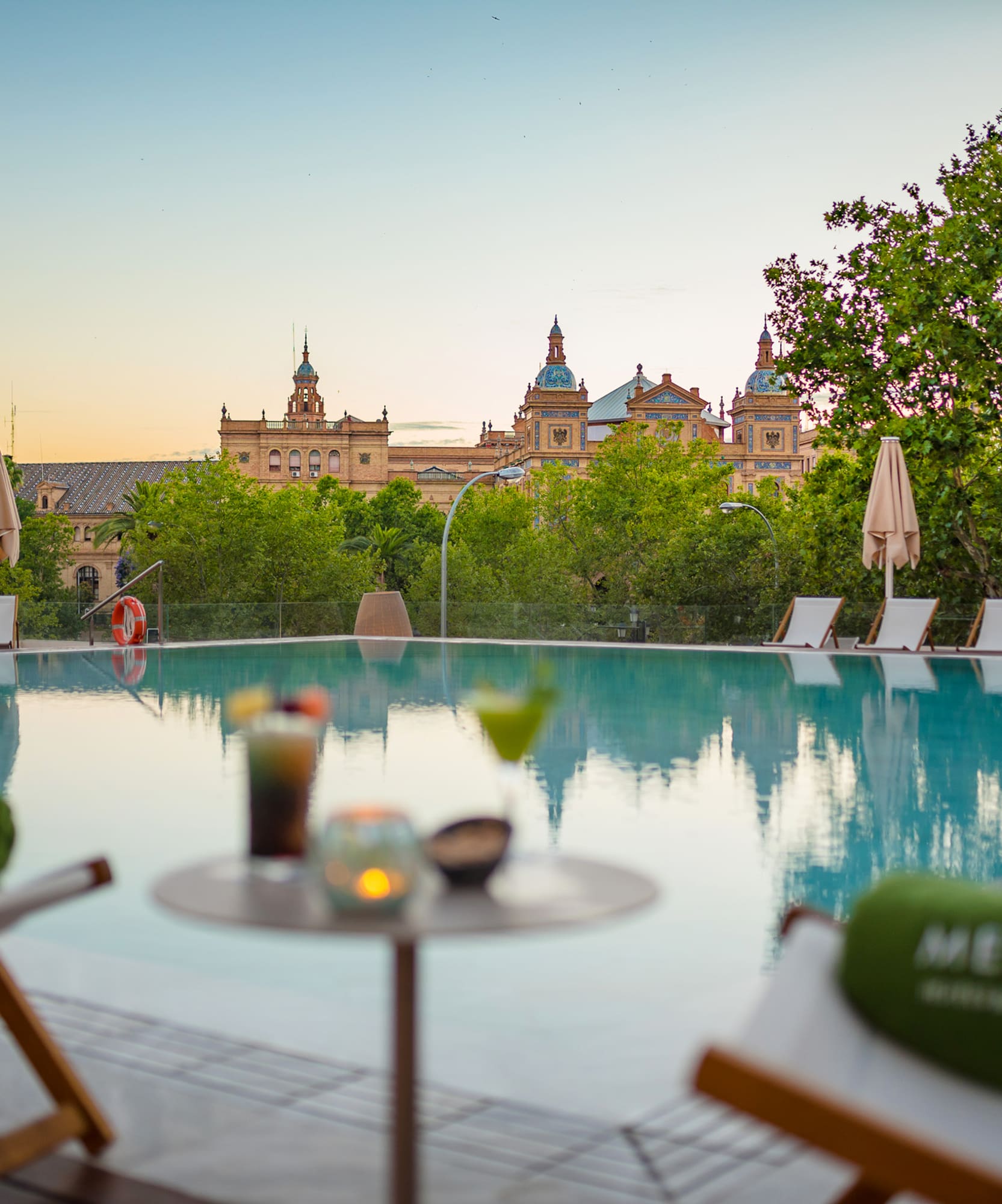 a pool with chairs and a table with a building in the background