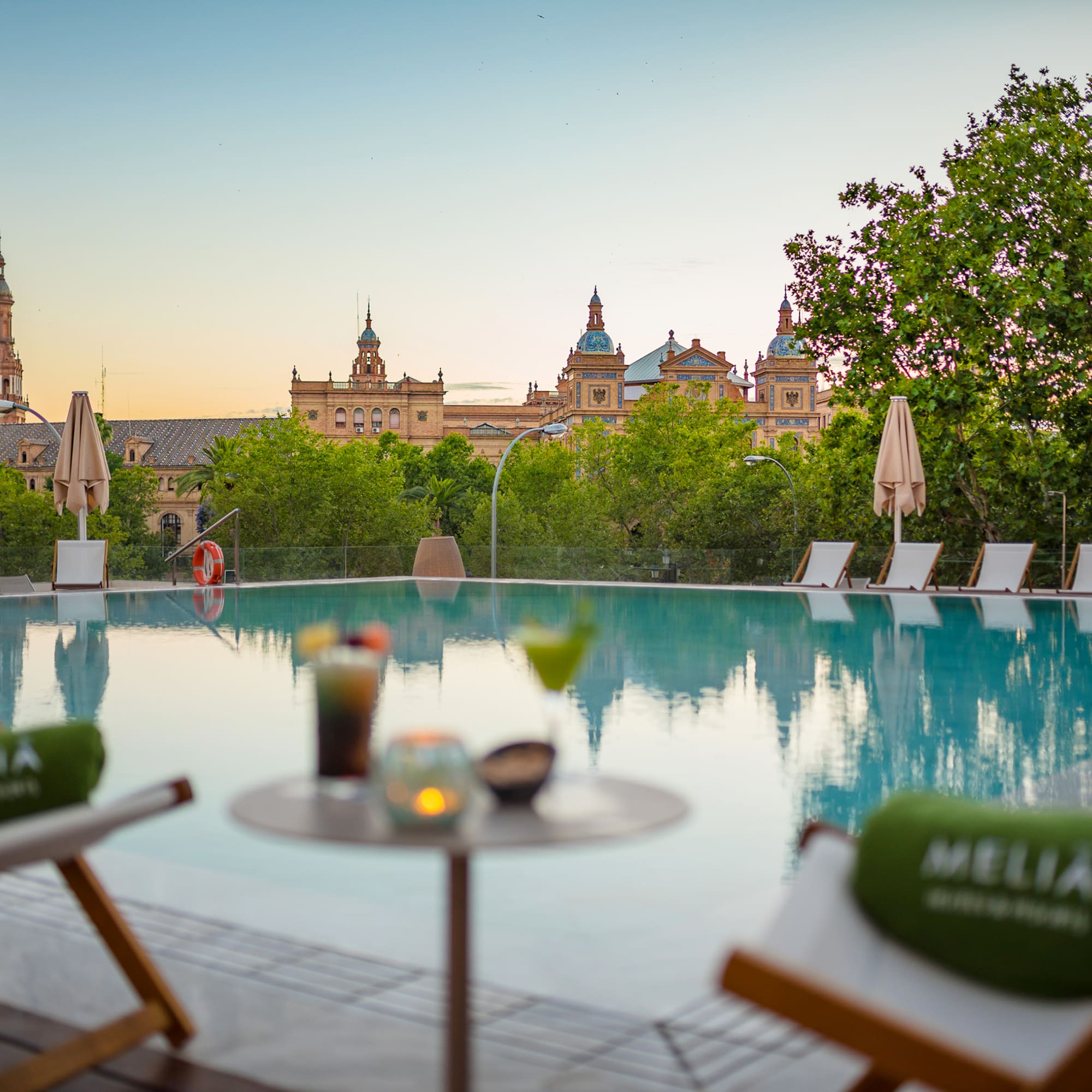 a pool with chairs and a table with a building in the background
