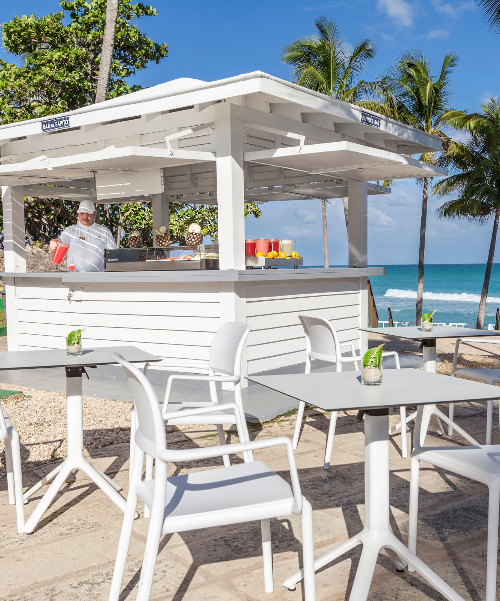 a white outdoor restaurant with tables and chairs on a beach