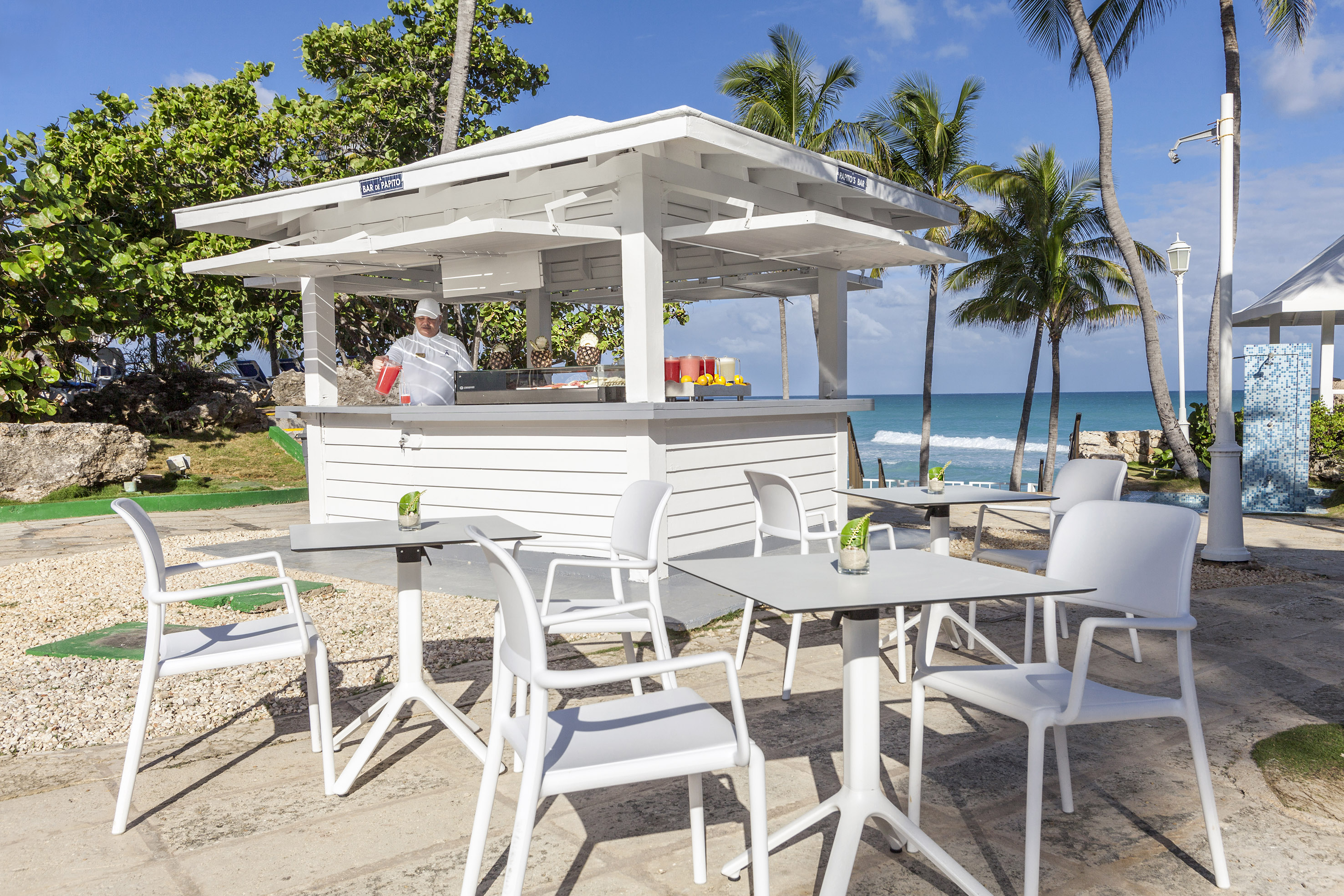 a white outdoor restaurant with tables and chairs on a beach