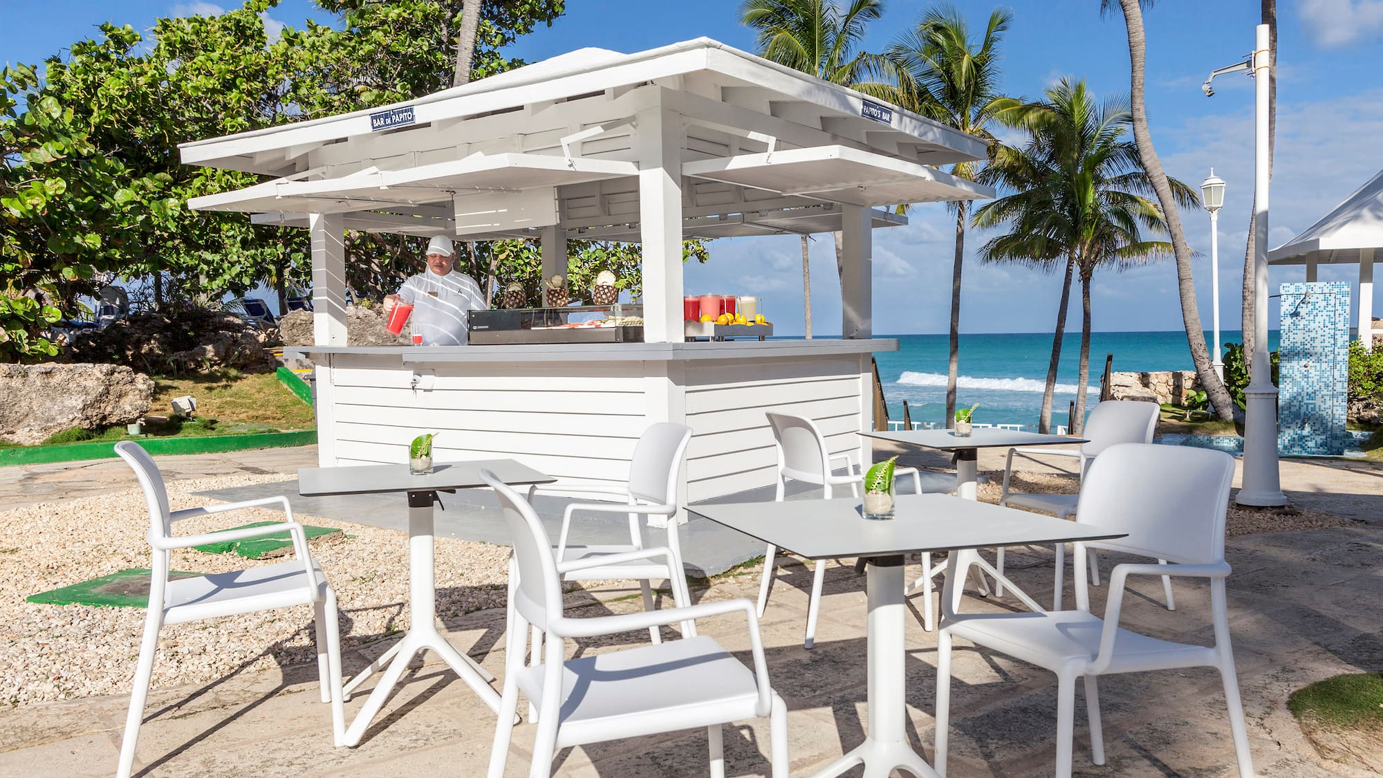 a white outdoor restaurant with tables and chairs on a beach