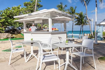 a white outdoor restaurant with tables and chairs on a beach