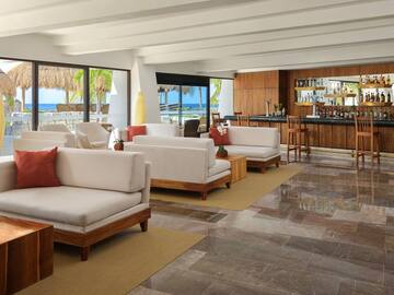 a room with white furniture and a bar