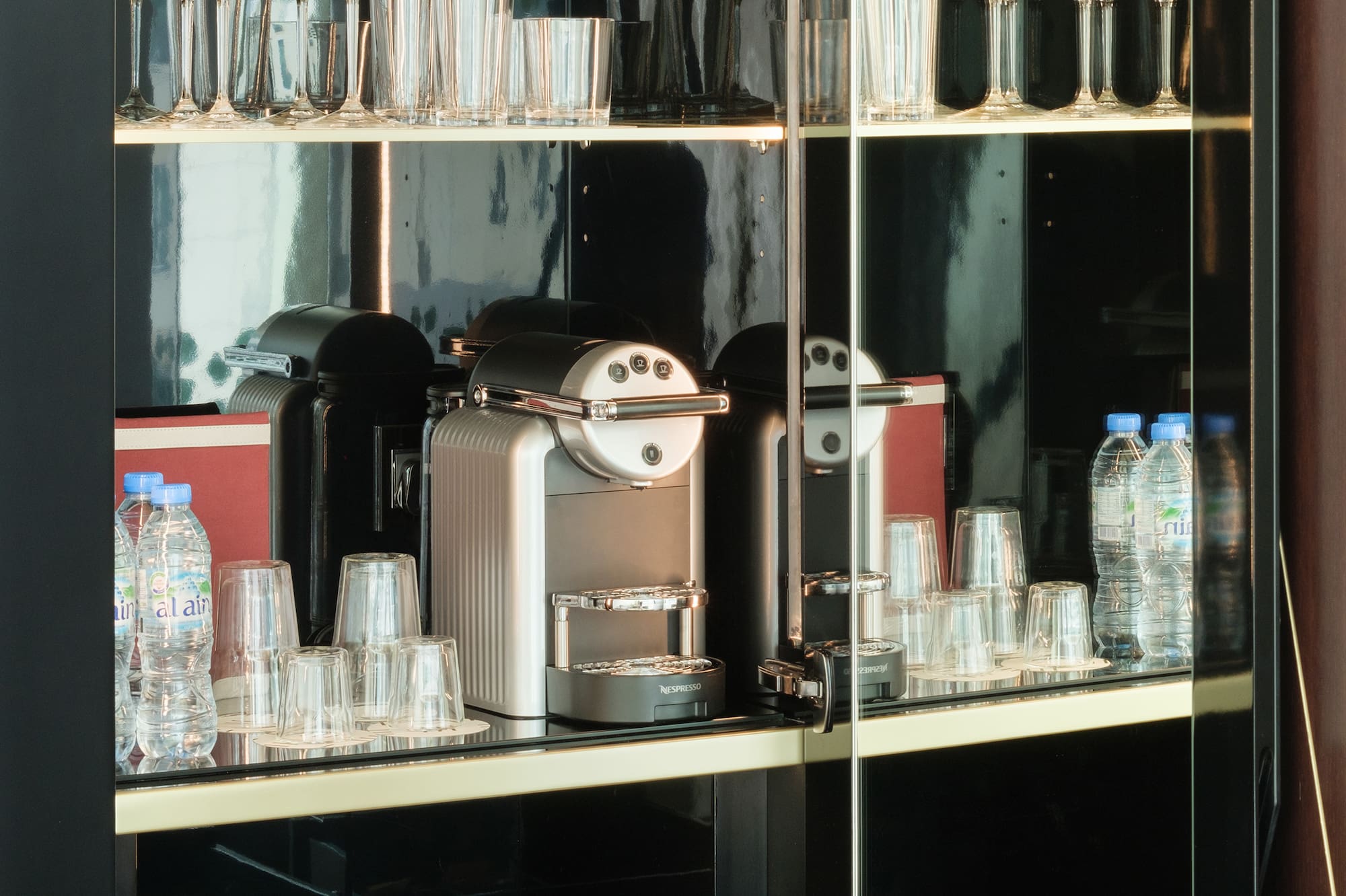 a glass cabinet with a coffee machine and glasses