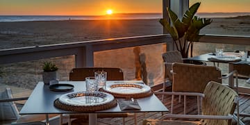 a table with plates and glasses on it with a sunset in the background