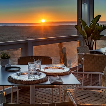 a table with plates and glasses on it with a sunset in the background