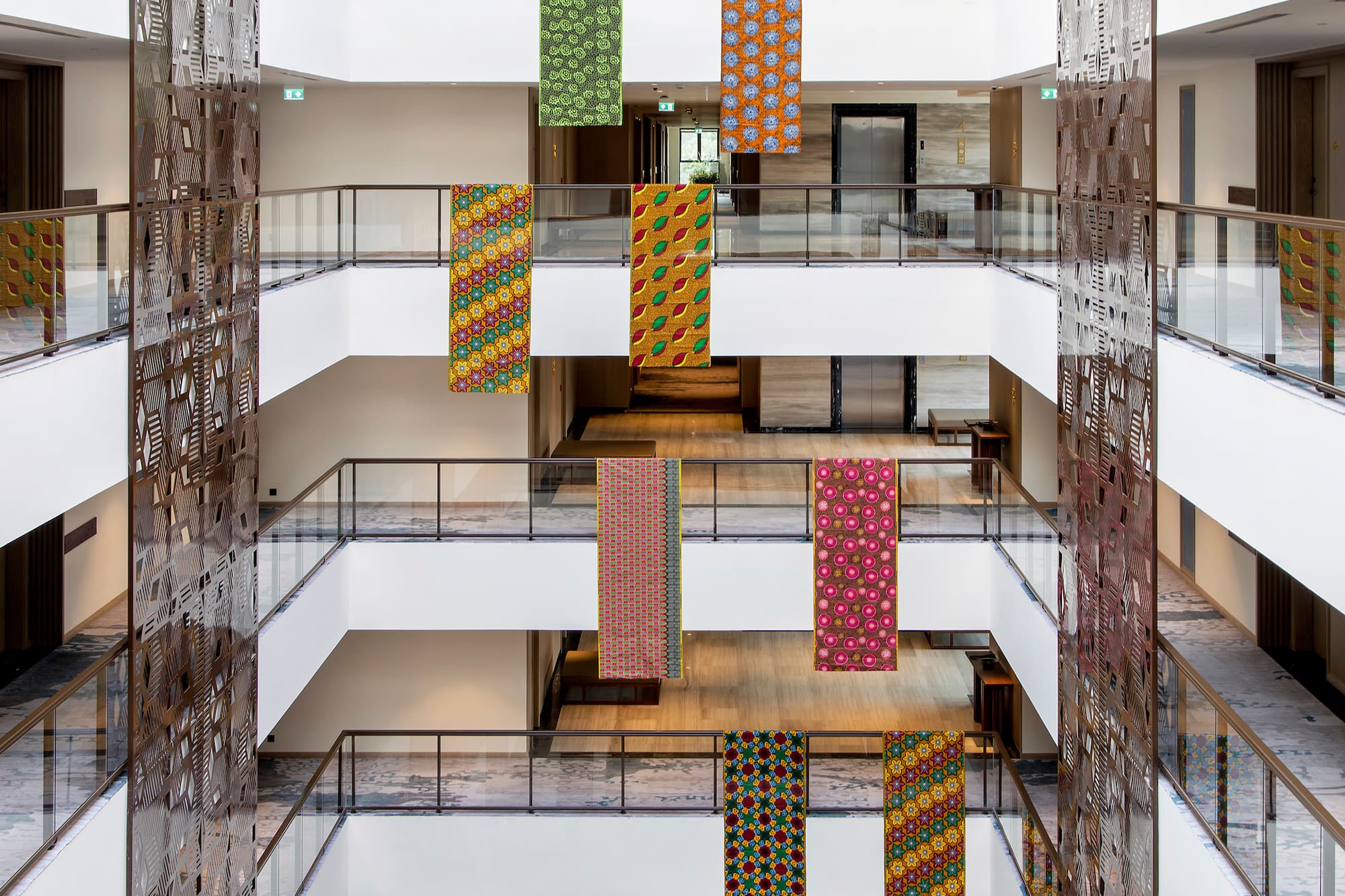 Hotel atrium with colorful patterned hanging banners and decorative screens.