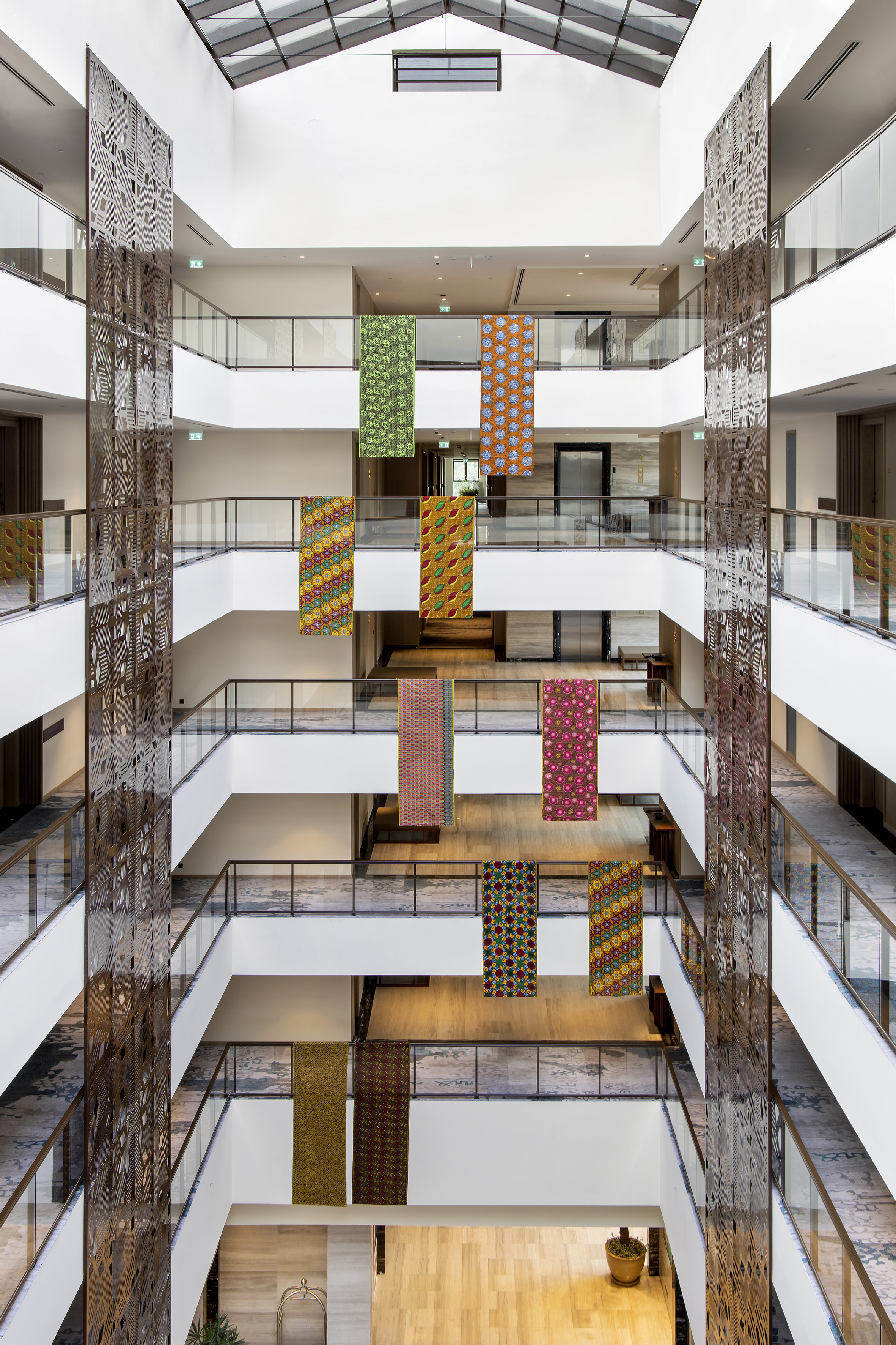 Hotel atrium with colorful patterned hanging banners and decorative screens.
