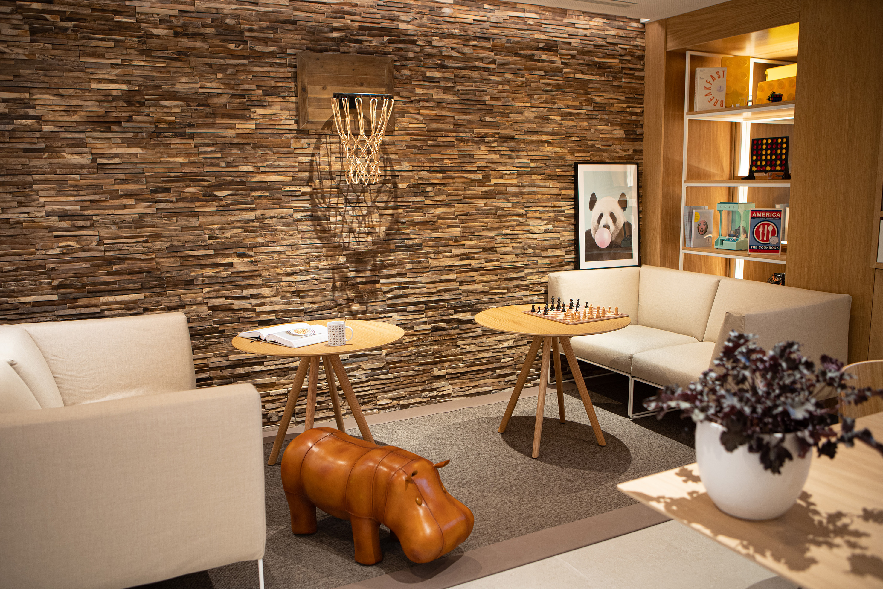 Cozy modern lounge: wood accent wall, basketball hoop, chessboard, leather hippo.