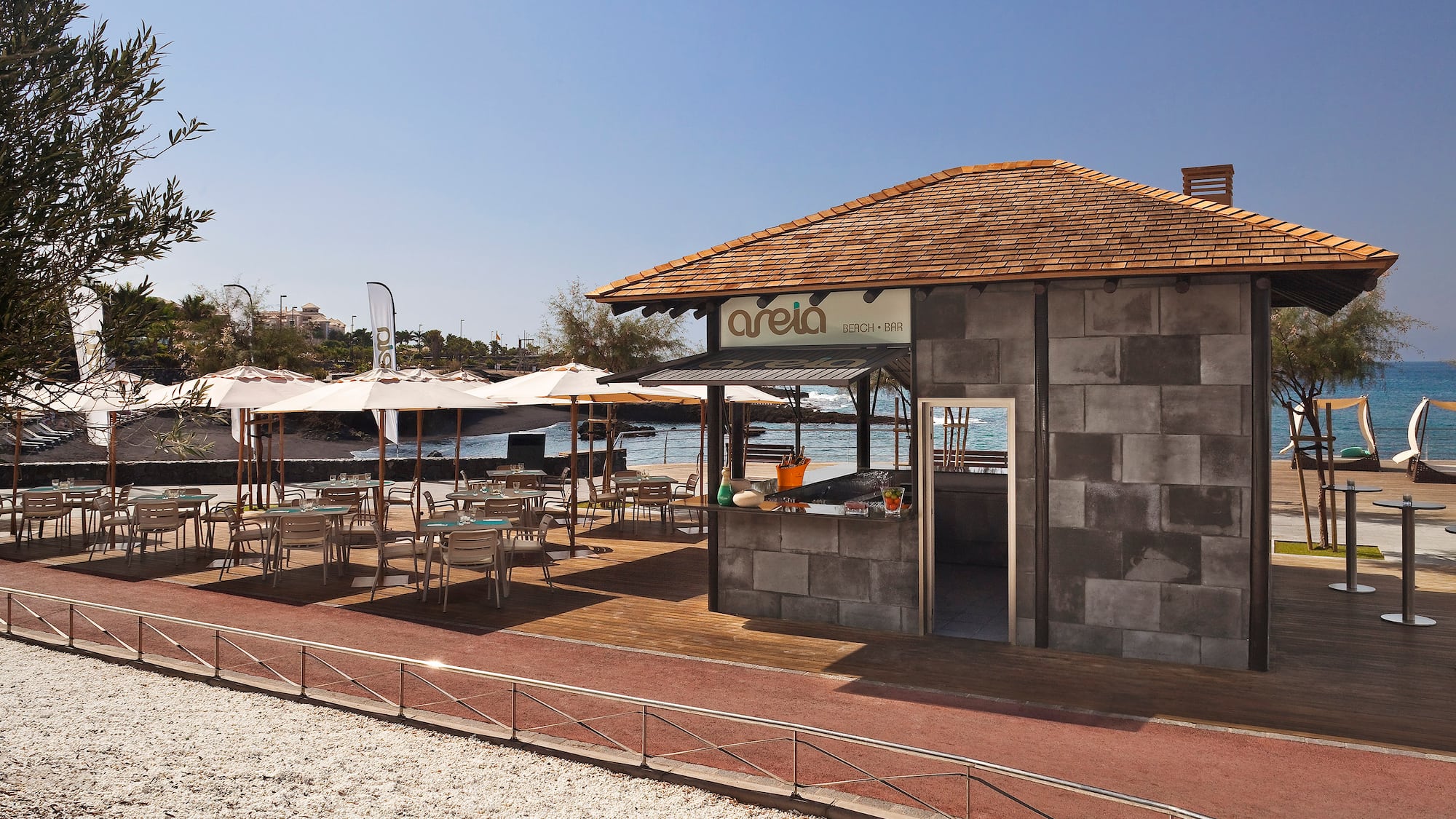 a building with tables and umbrellas on a beach