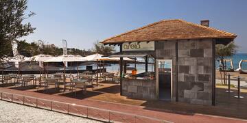 a building with tables and umbrellas on a beach