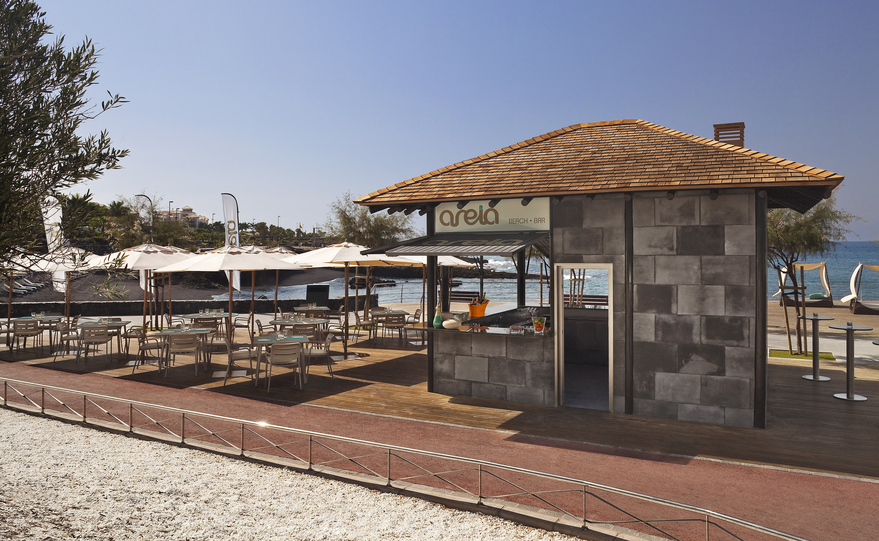 a building with tables and umbrellas on a beach